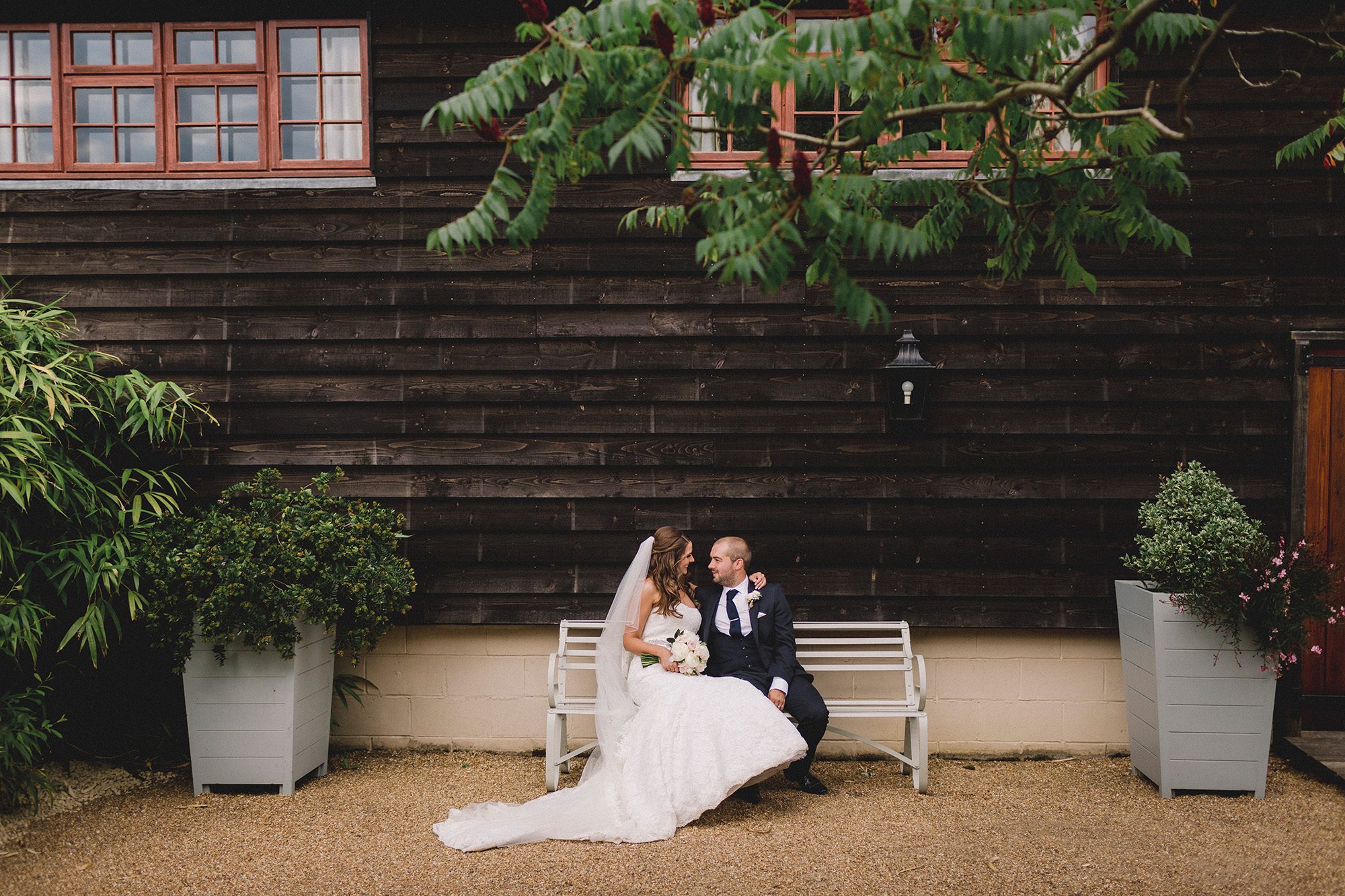 Bride and groom hug closely as they sit on a bench at Gate Street Barn wedding venue.