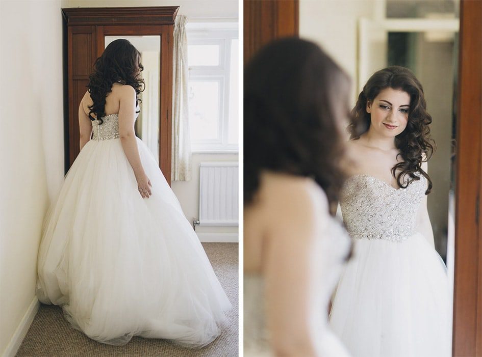 Bride admiring her dress in the mirror.