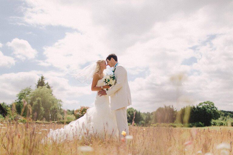 Bride and groom hug closely on their wedding day at Cain Manor in Surrey.