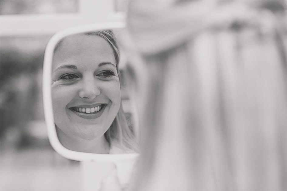 Bride looks in the mirror as she smiles.
