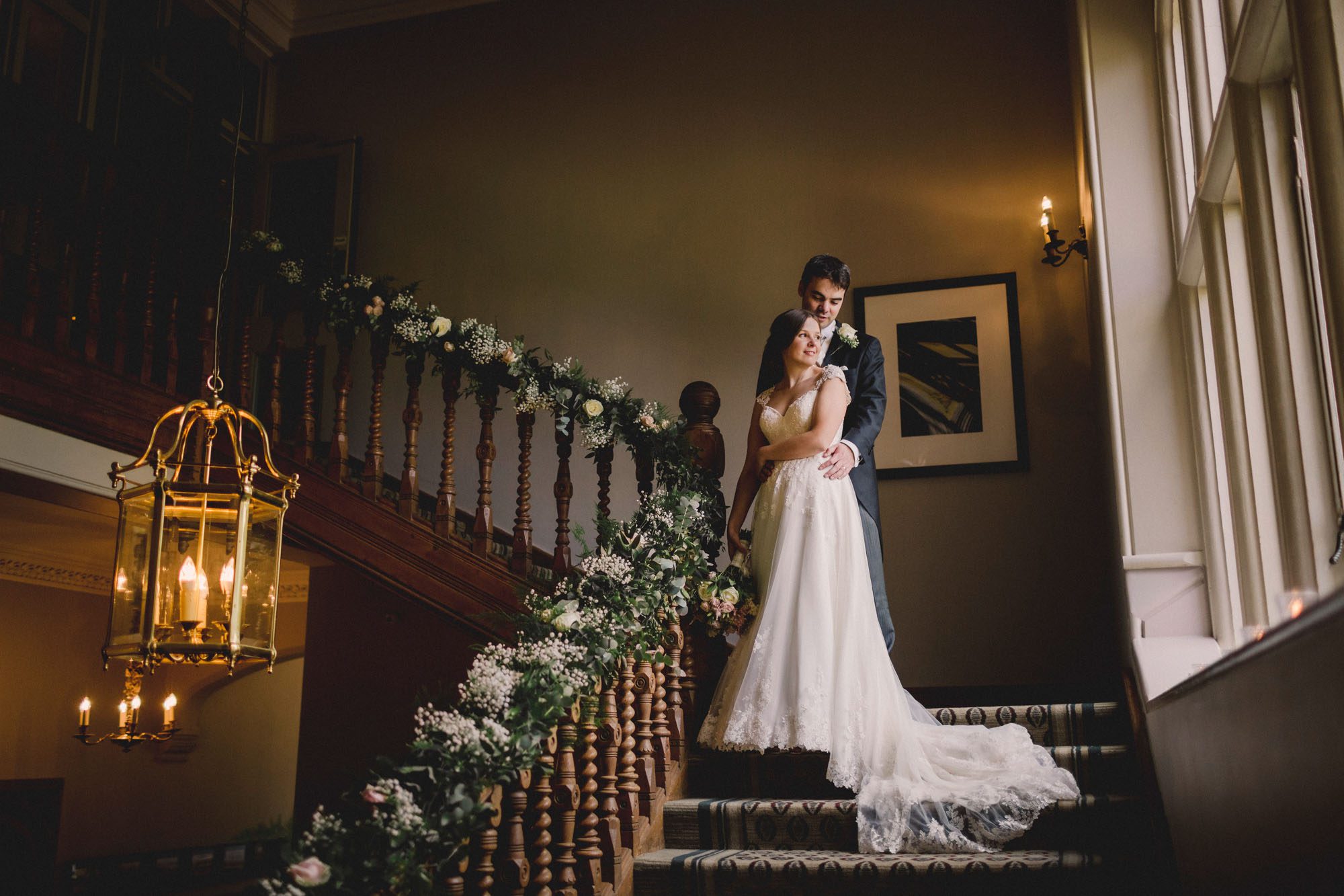 Bride and groom hug closely on the grand staircase on their wedding day at Hartsfield Manor.