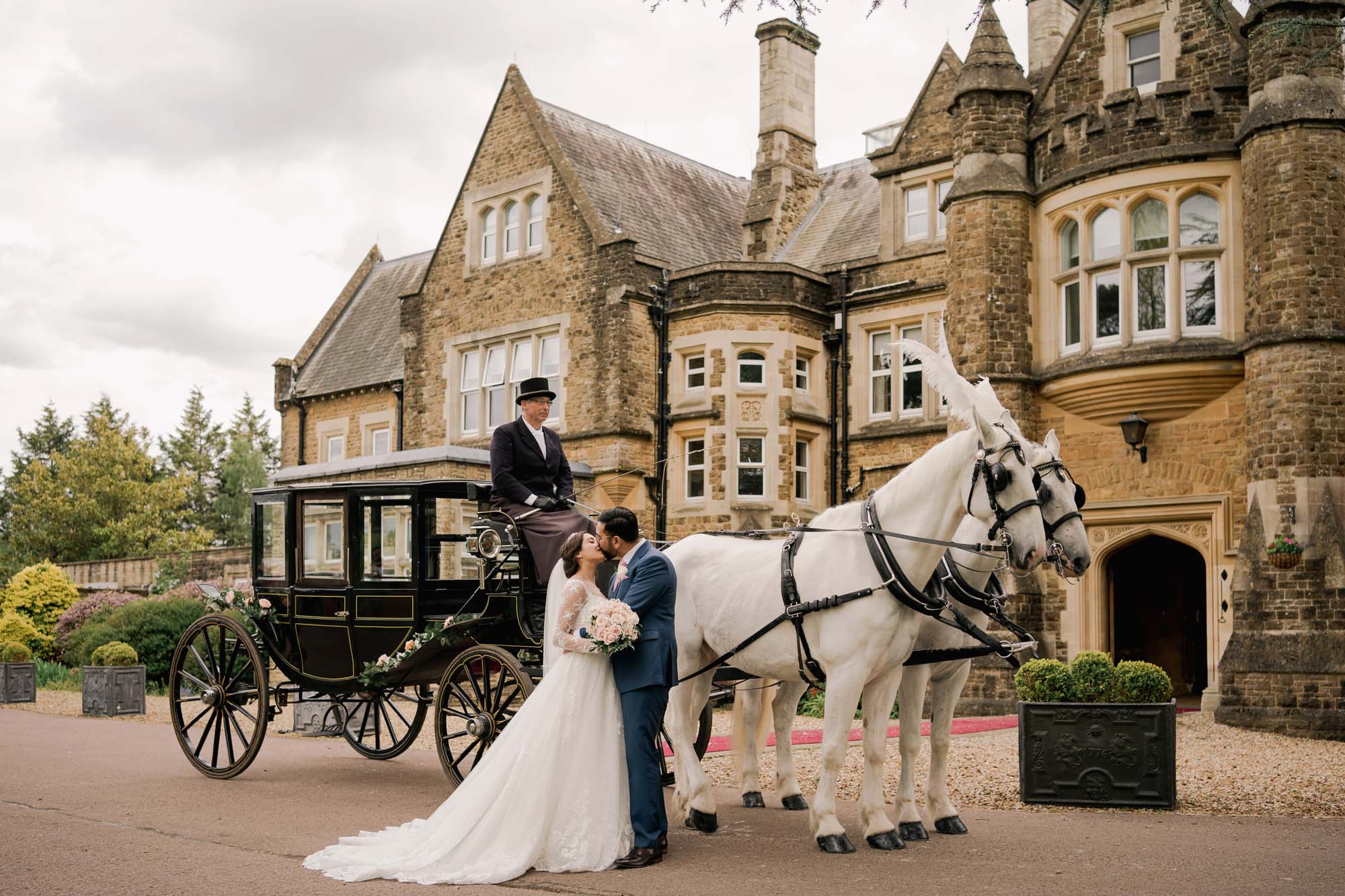 Bride and groom kiss on their wedding day in front of a horse and cart at Hartsfield Manor.