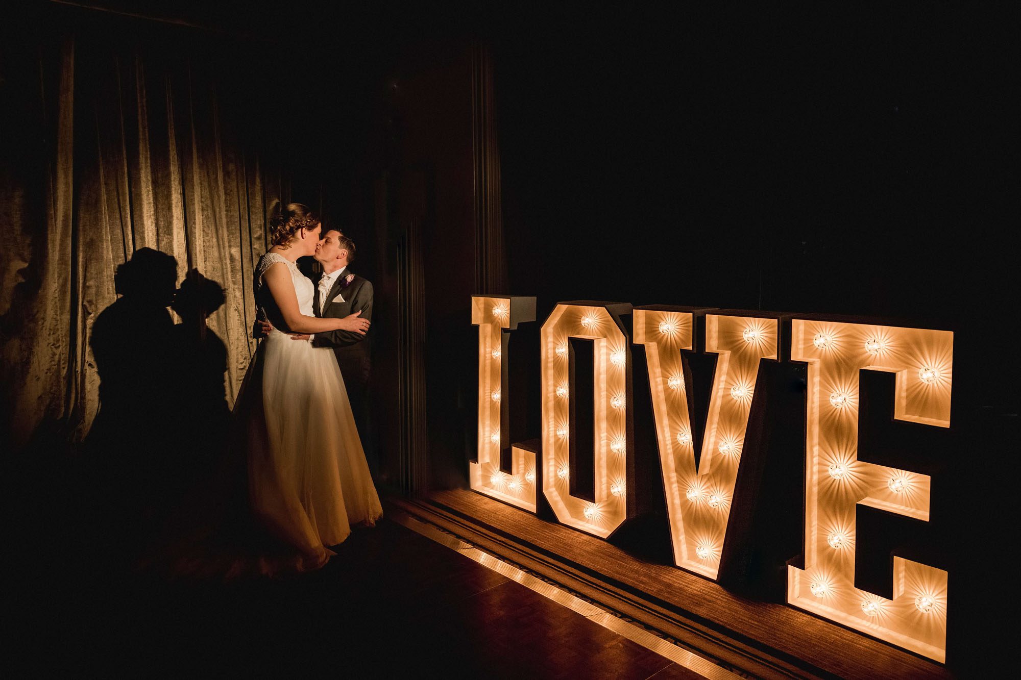 Bride and groom kiss on their wedding day in front of a love sign at Hartsfield Manor.
