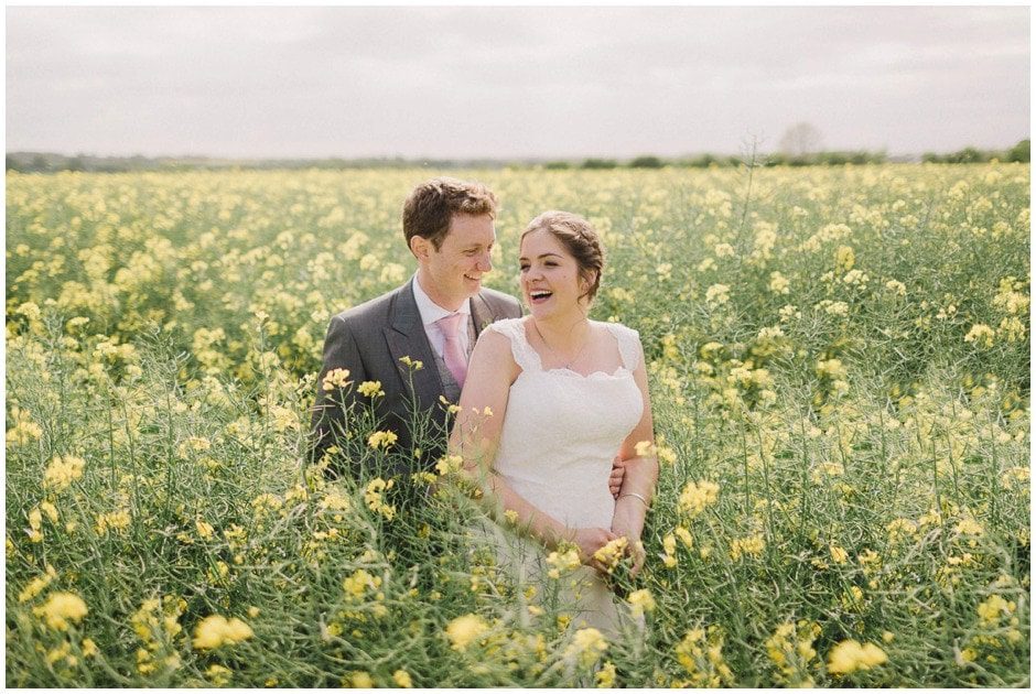 A bride and groom at their wedding in the rapeseed field at Crows Hall in Suffolk.