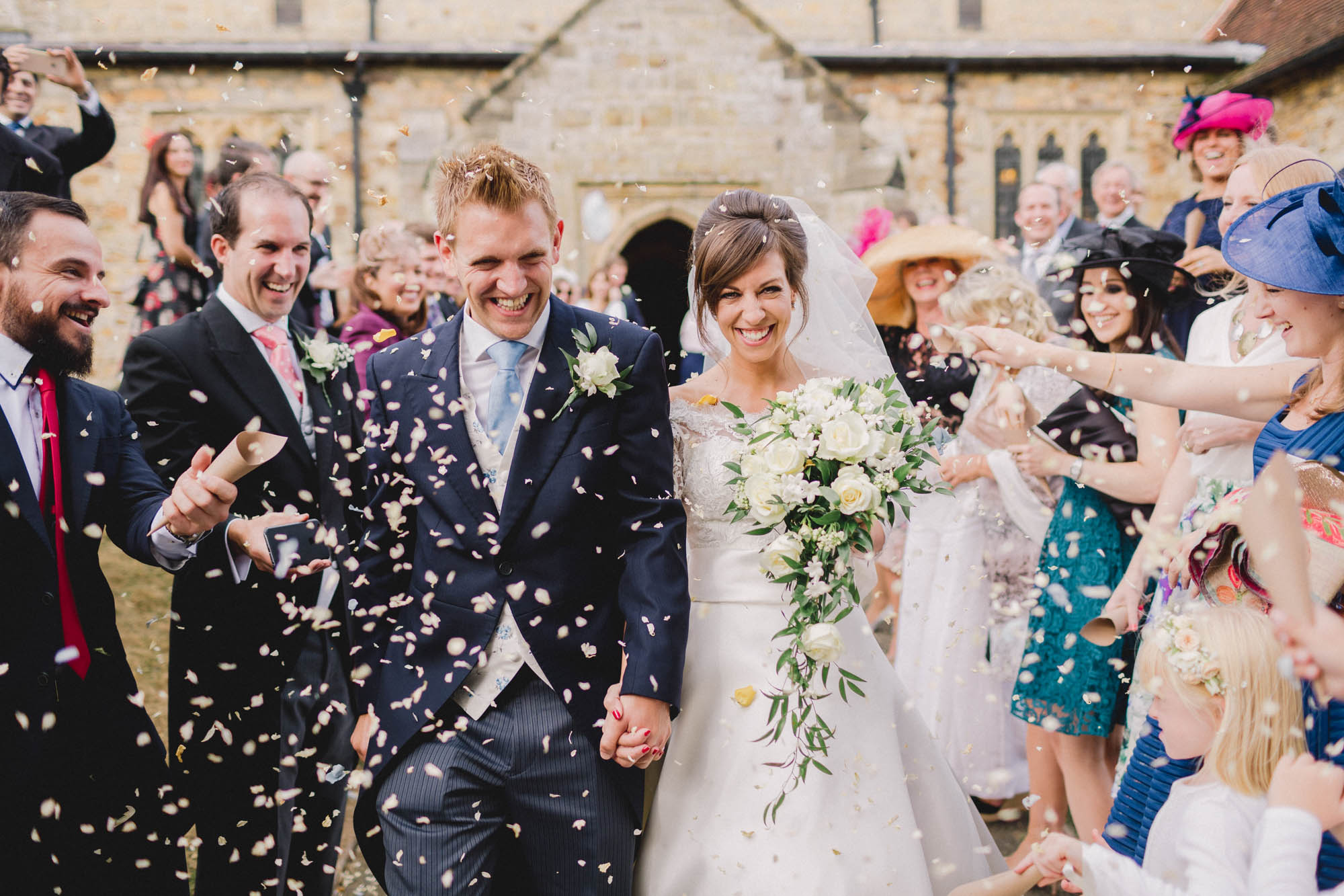 Wedding guests throw confetti at the bride and groom on their wedding day Ashdown Park Wedding Venue in Sussex.