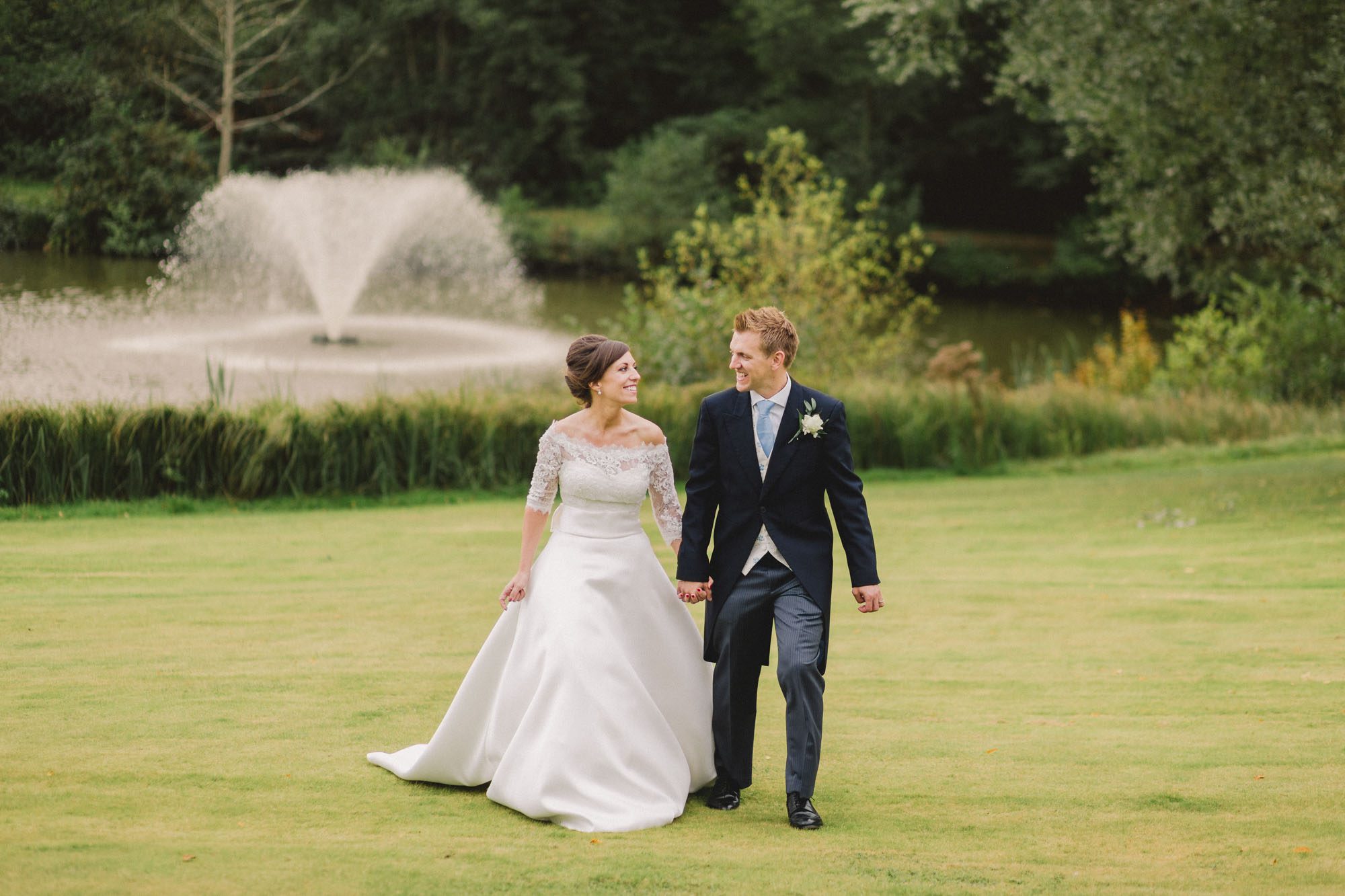 Bride and groom smiling whilst they take a stroll on their wedding day at Ashdown Park Wedding Venue in Sussex.