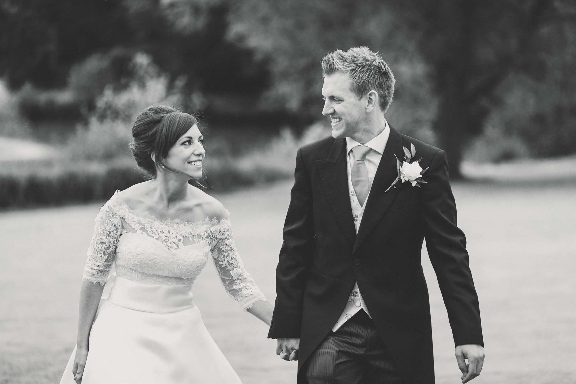 Bride and groom smiling whilst they take a stroll on their wedding day at Ashdown Park Wedding Venue in Sussex.