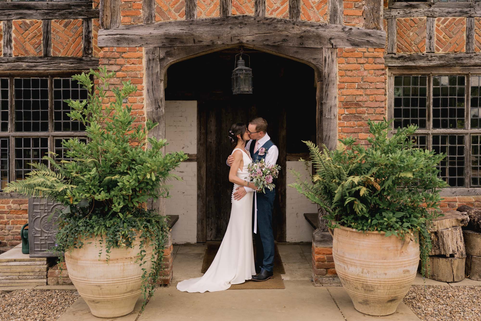 A bride and groom share a kiss in the doorway at Dorney Court in Buckinghamshire.