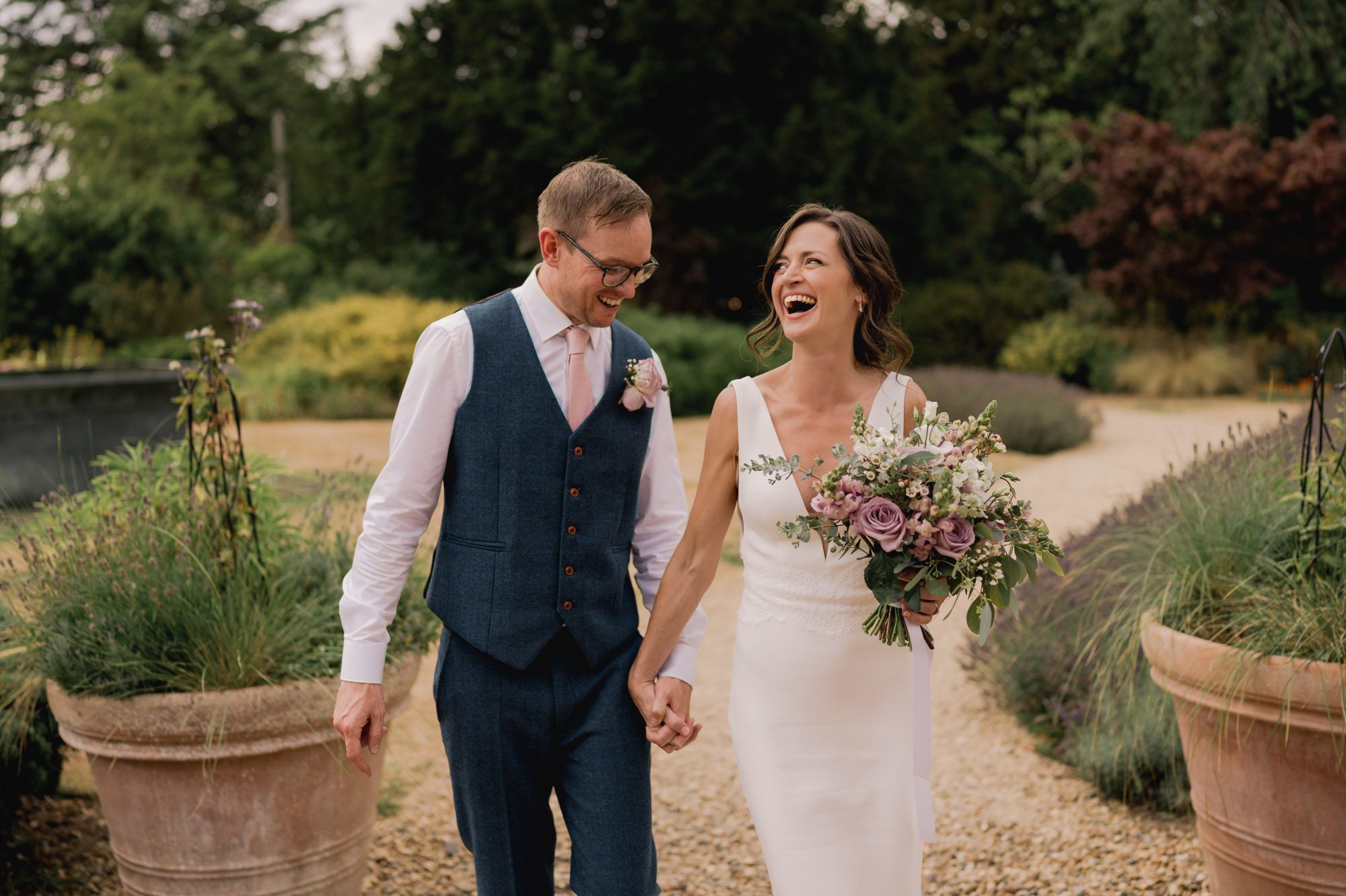 A bride and groom share laughter as they take a stroll on their wedding day at Dorney Court in Buckinghamshire.