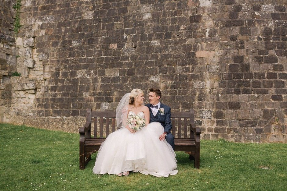 Bride and Groom sitting on a bemch at Farnham Castle in Surrey.