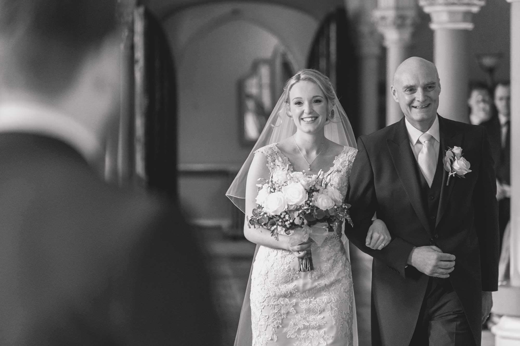A bride walks down the aisle with her father in the Old Library at Wotton House in Surrey.
