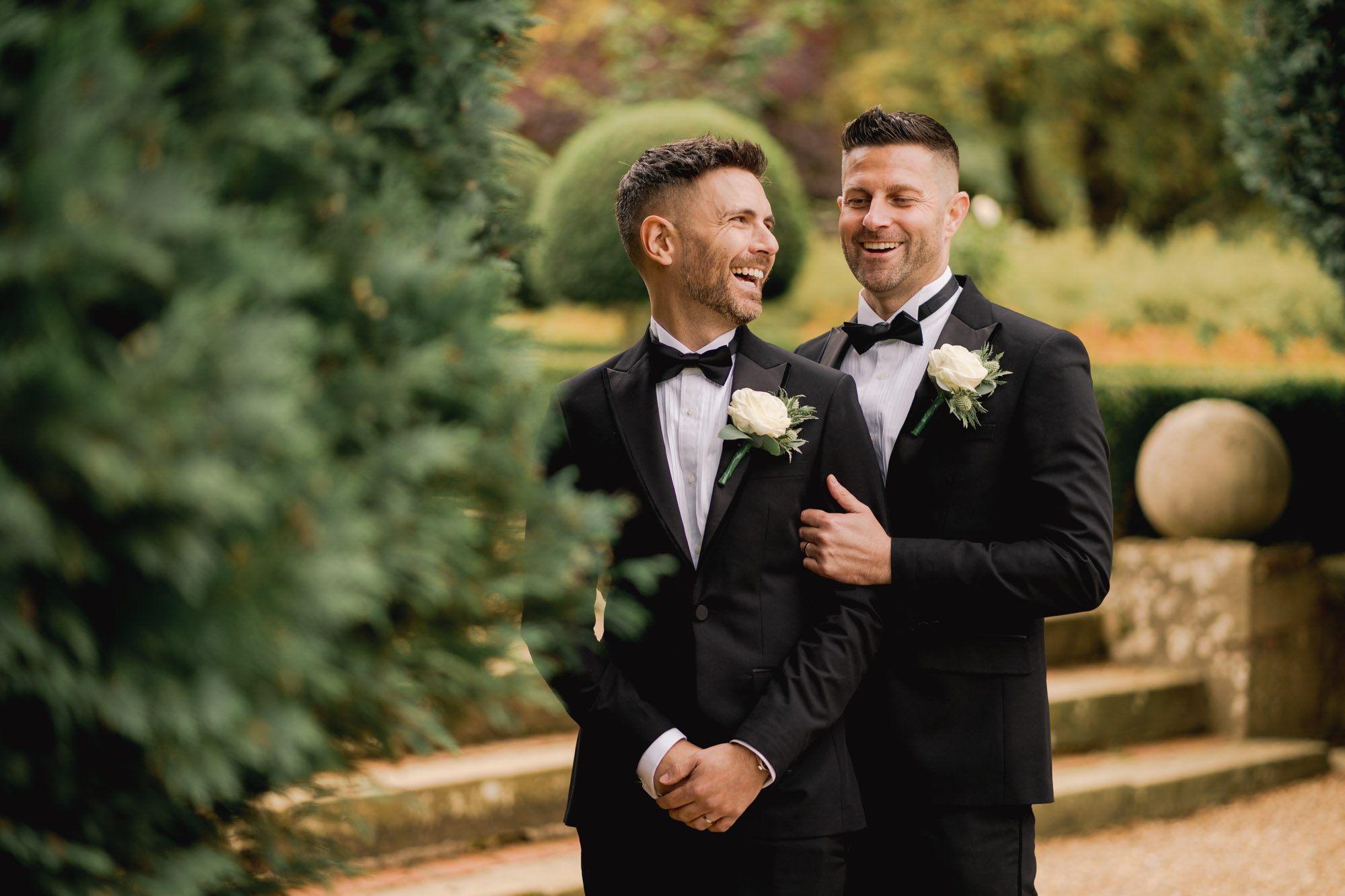 Two grooms laugh together on their wedding dayat Wotton House.