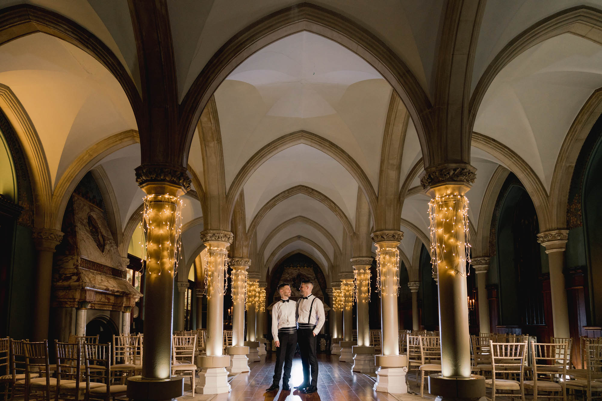 Two grooms hugging in the Old Library at Wotton House.