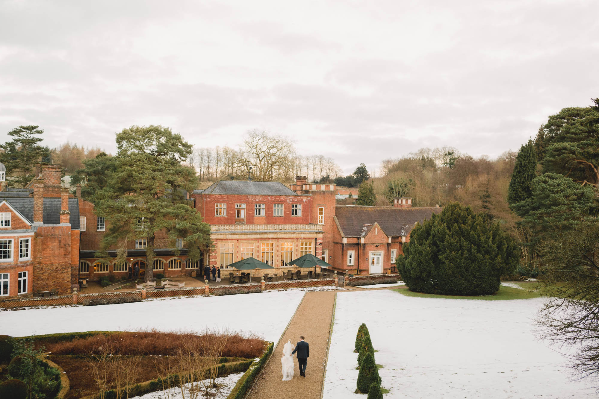 Bride and groom smiling whilst they take a stroll on their wedding day in Winter at Wotton House Hotel.