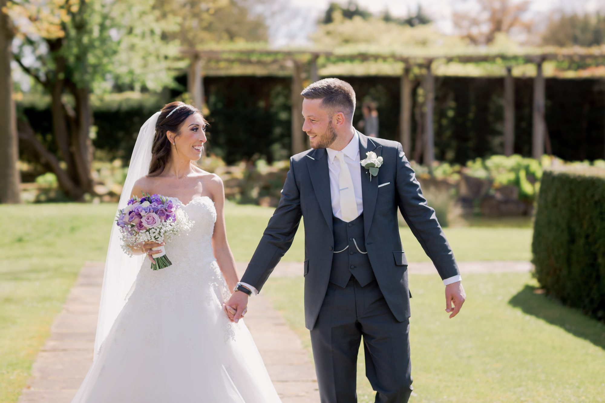 Bride and groom smiling whilst they take a stroll on their wedding day at Great Fosters.