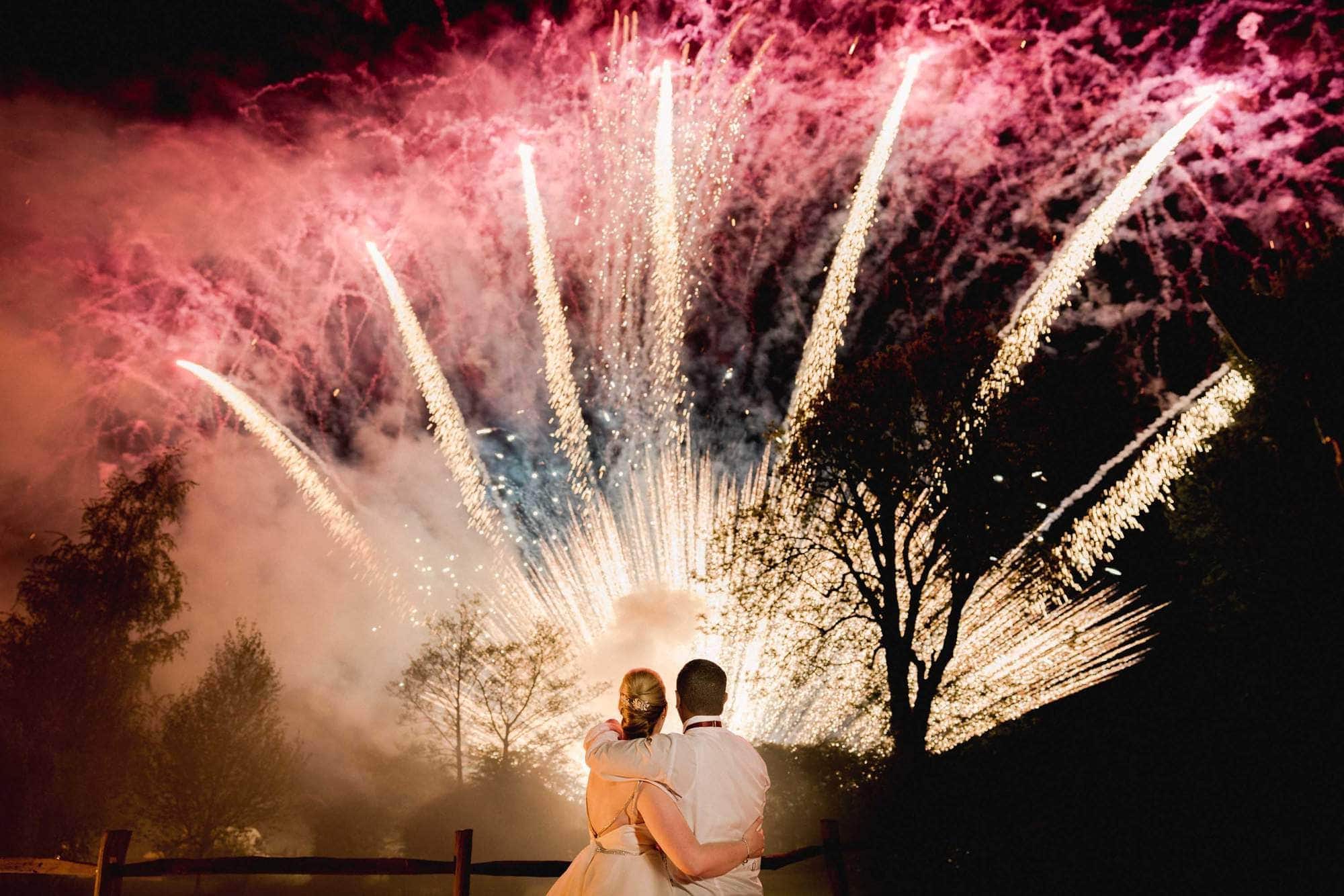 Bride and groom watching platinum fireworks at Coltsford Mill in Surrey