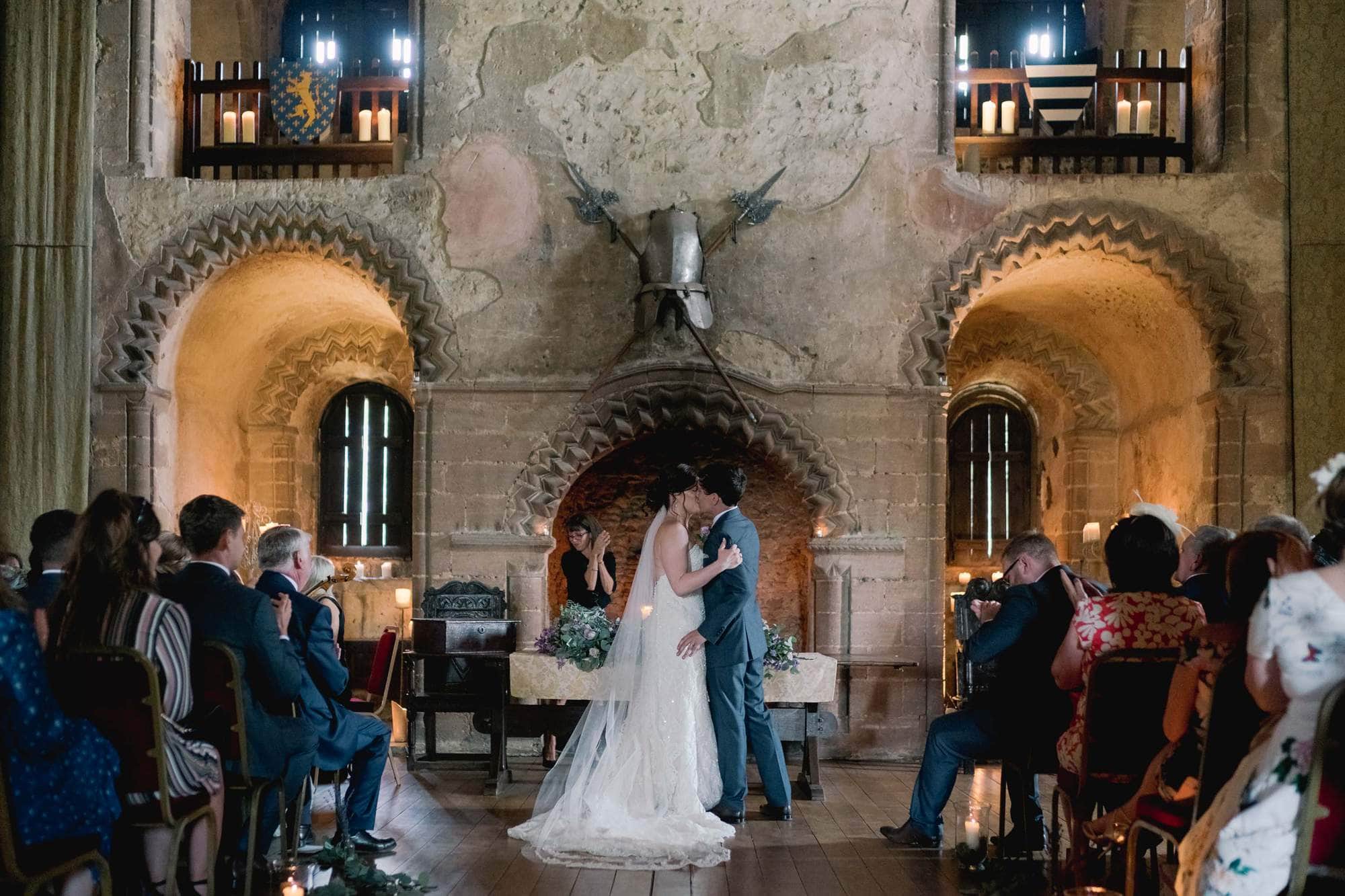Bride and groom kiss during their wedding ceremony in the castle.