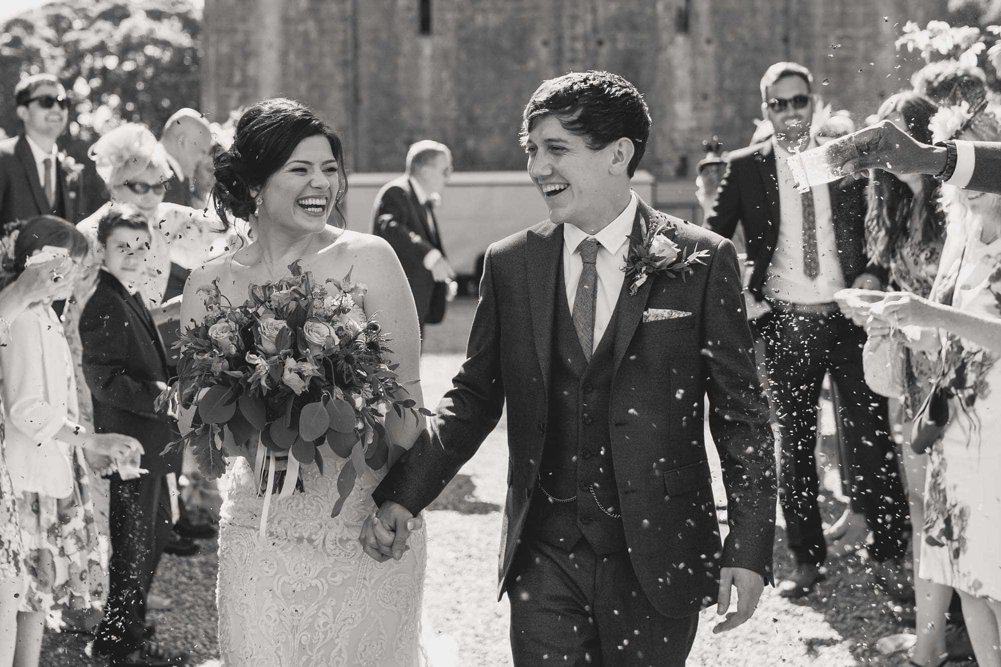 Wedding guests throw confetti at the bride and groom on their wedding day at Hedingham Castle.