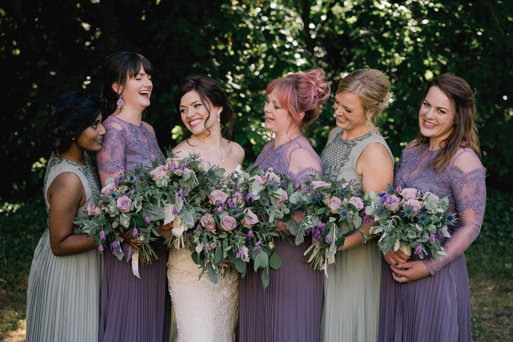 Bride and her bridal party laugh with joy at Hedingham Castle in Essex.
