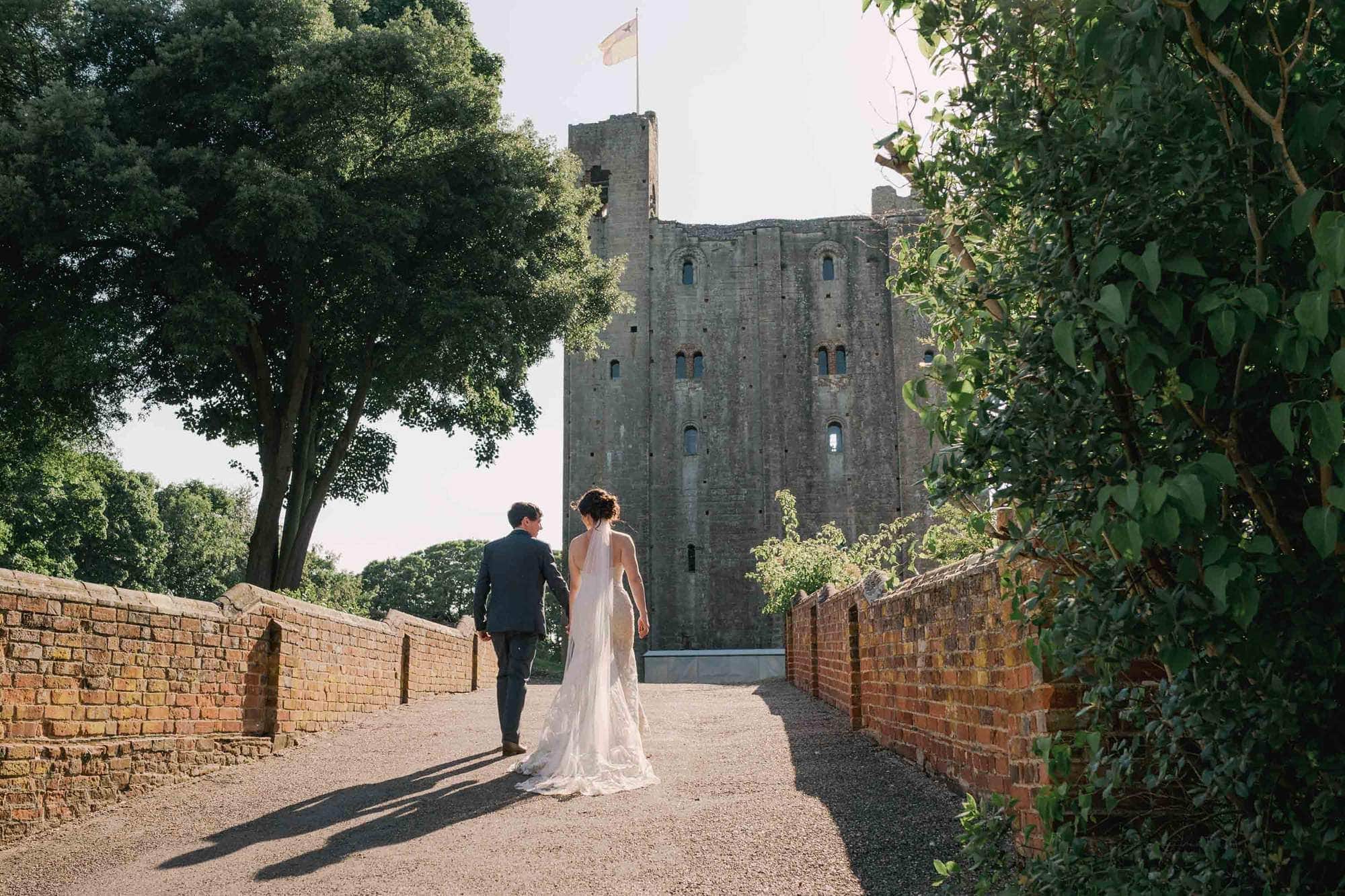 Bride and Groom walk across the Tudor bridge to Hedingham Castle in Essex.