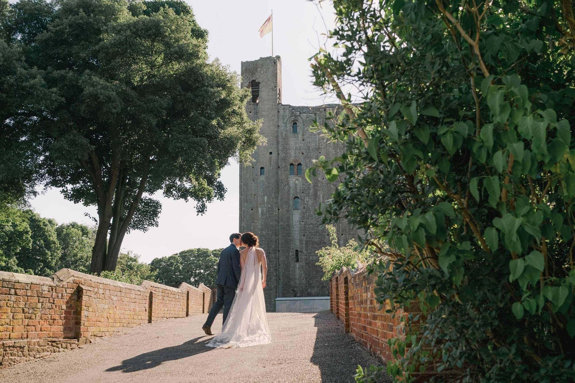 Bride and groom kiss on their wedding day at Hedingham Castle near Colchester in Essex.