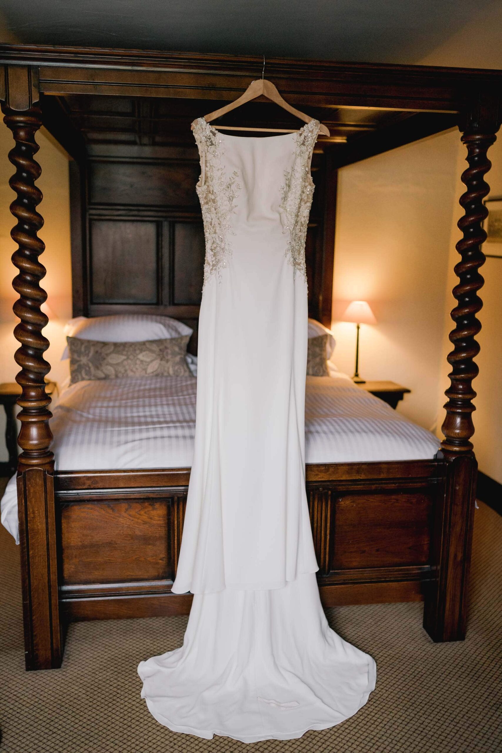 Wedding dress hanging on a four poster bed.