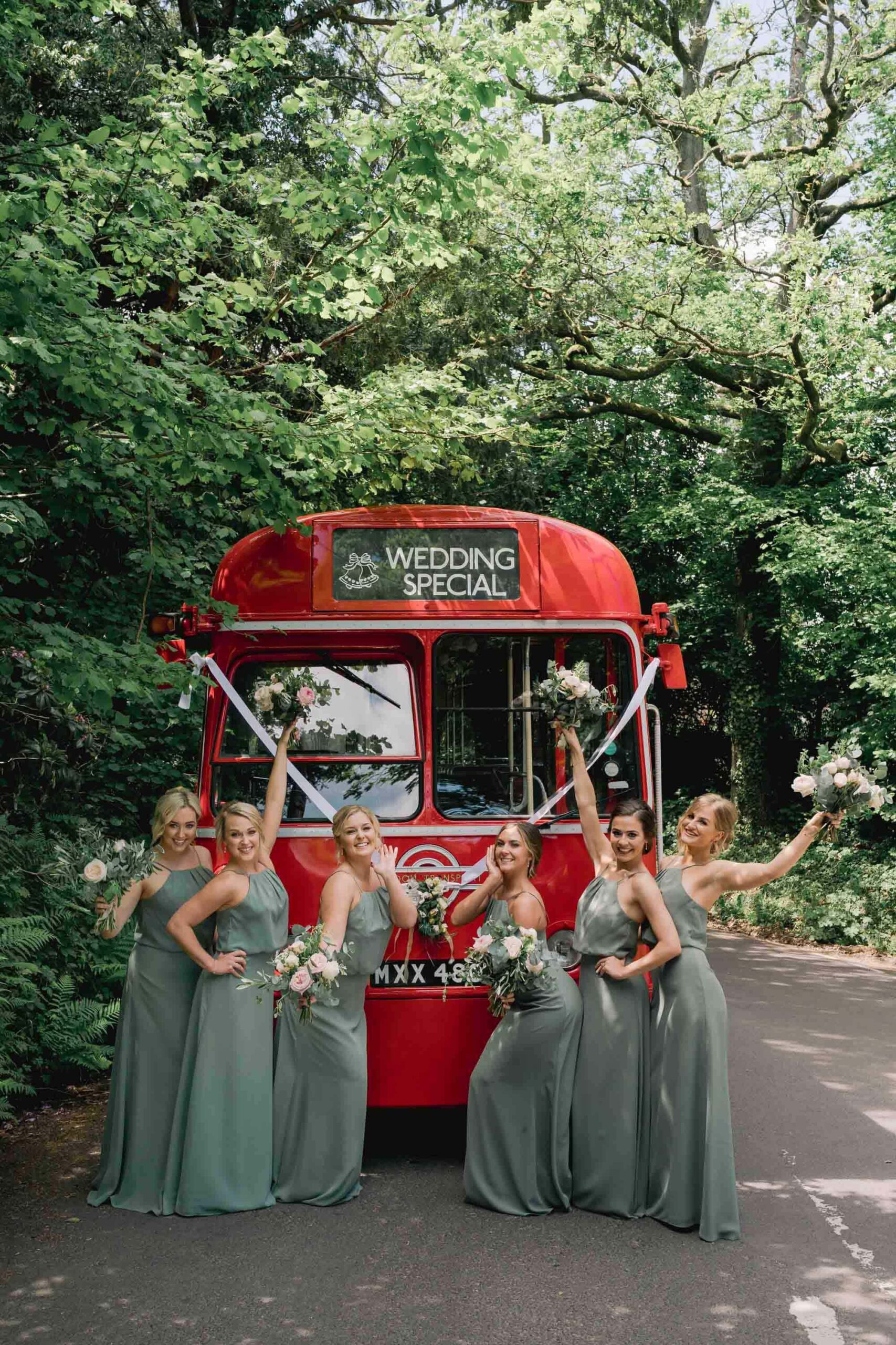 Wedding photography with bridesmaids posing in front of a red doubke decker bus.