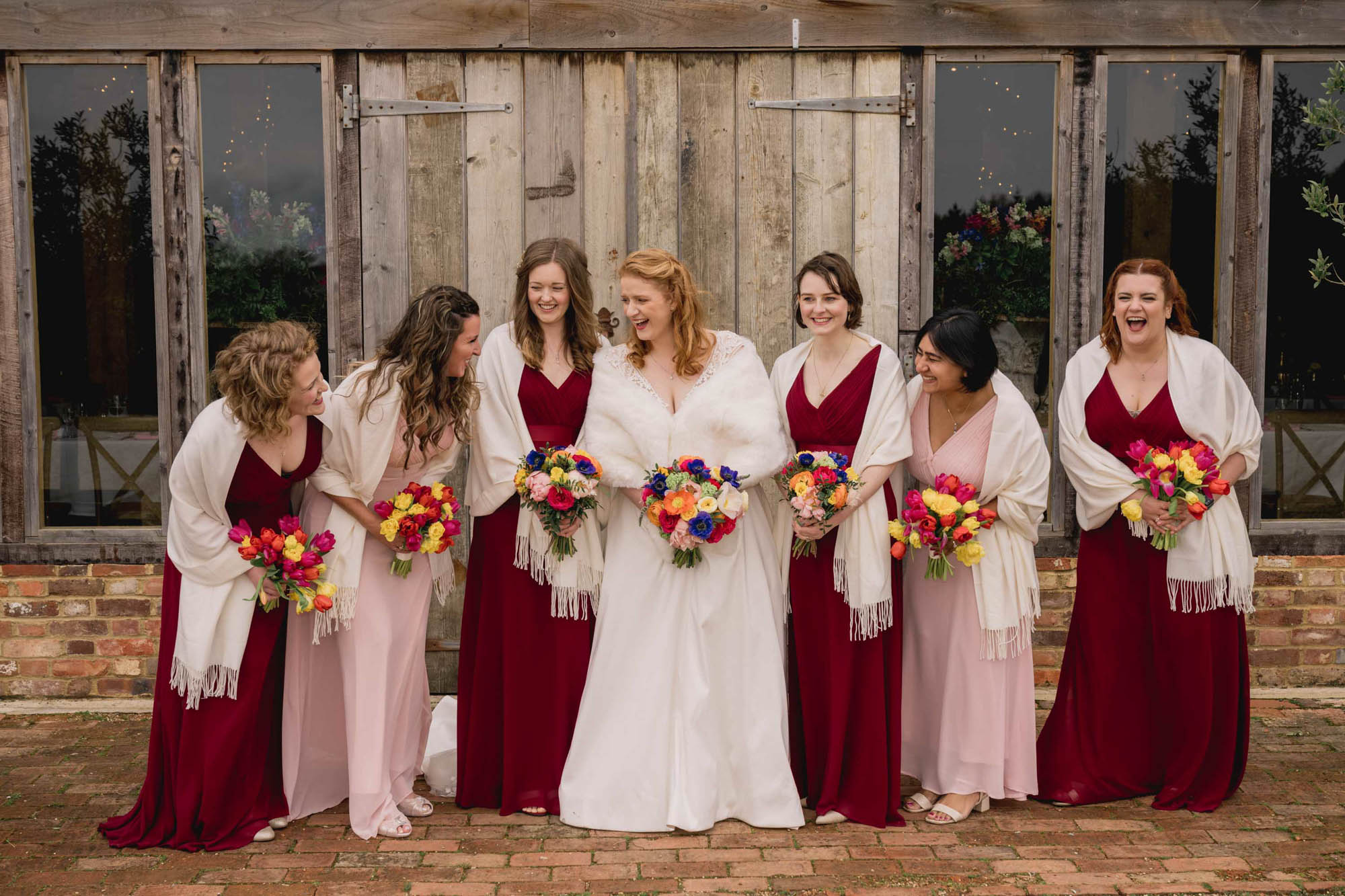 Bride and her bridesmaids laughing Bride and groom hug closely on their wedding day at High Billinghurst Farm in Surrey.