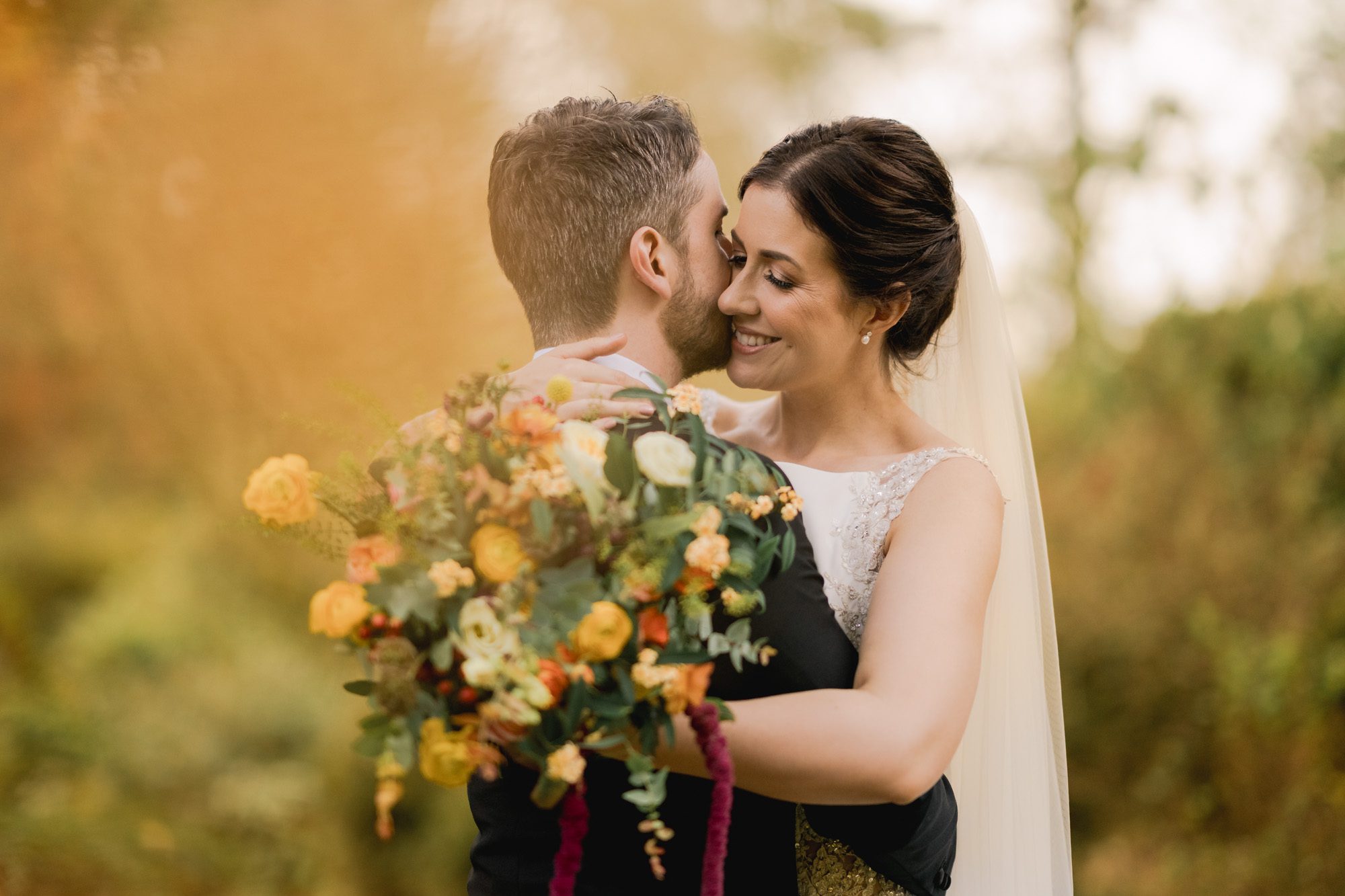 Bride and groom hug closely on their wedding day in Autumn at Ramster Hall in Chiddingfold.