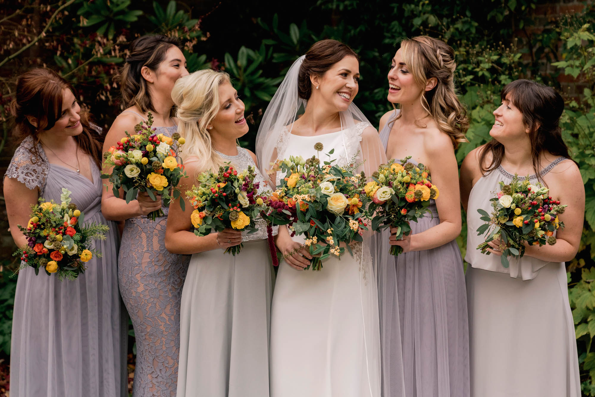 Bride laughs with her bridesmaids at Ramster Hall in Surrey.