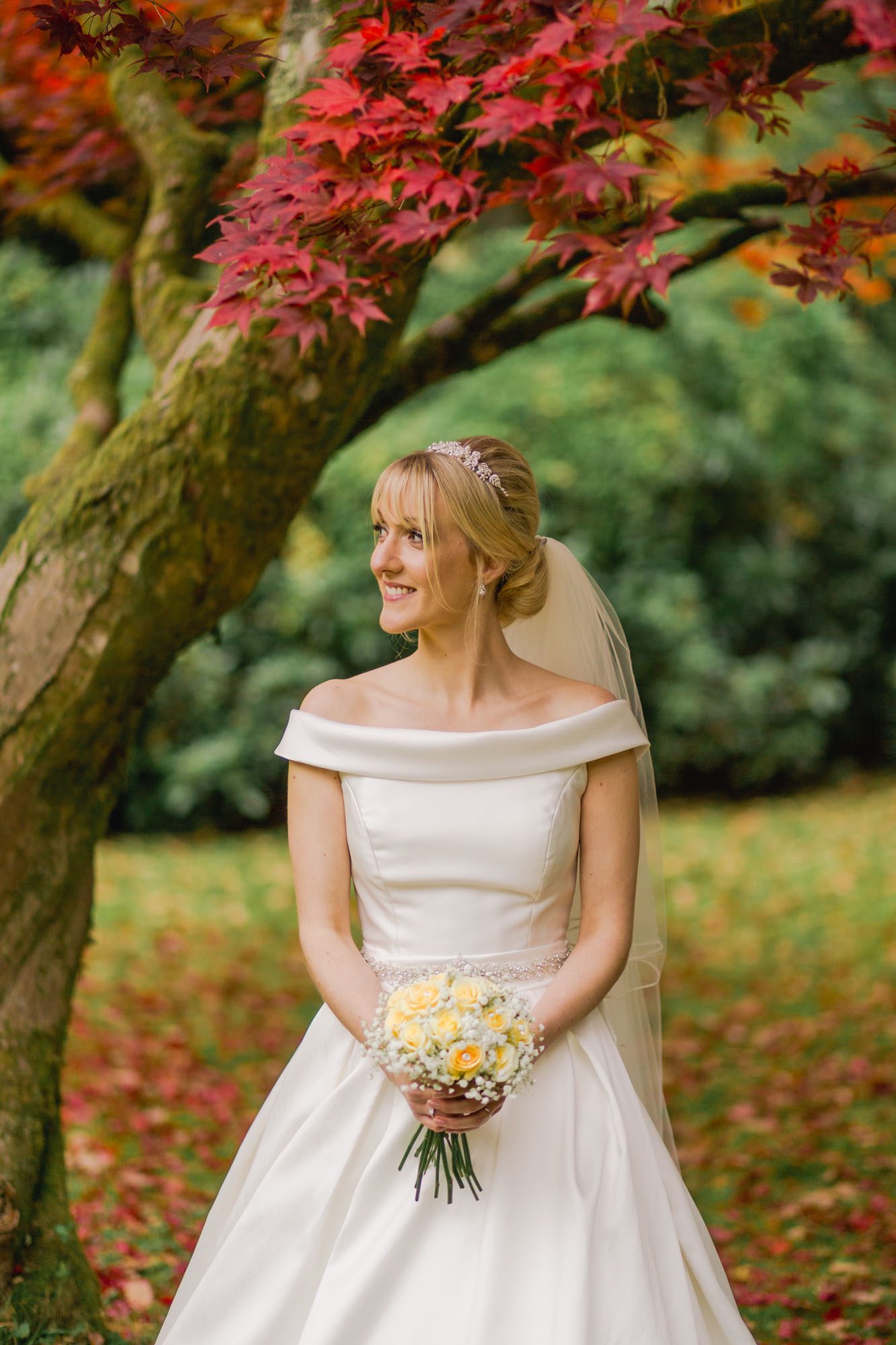 A bride in a beautiful wedding dress holding her bouquet of flowers in the Ramser gardens in Autumn.