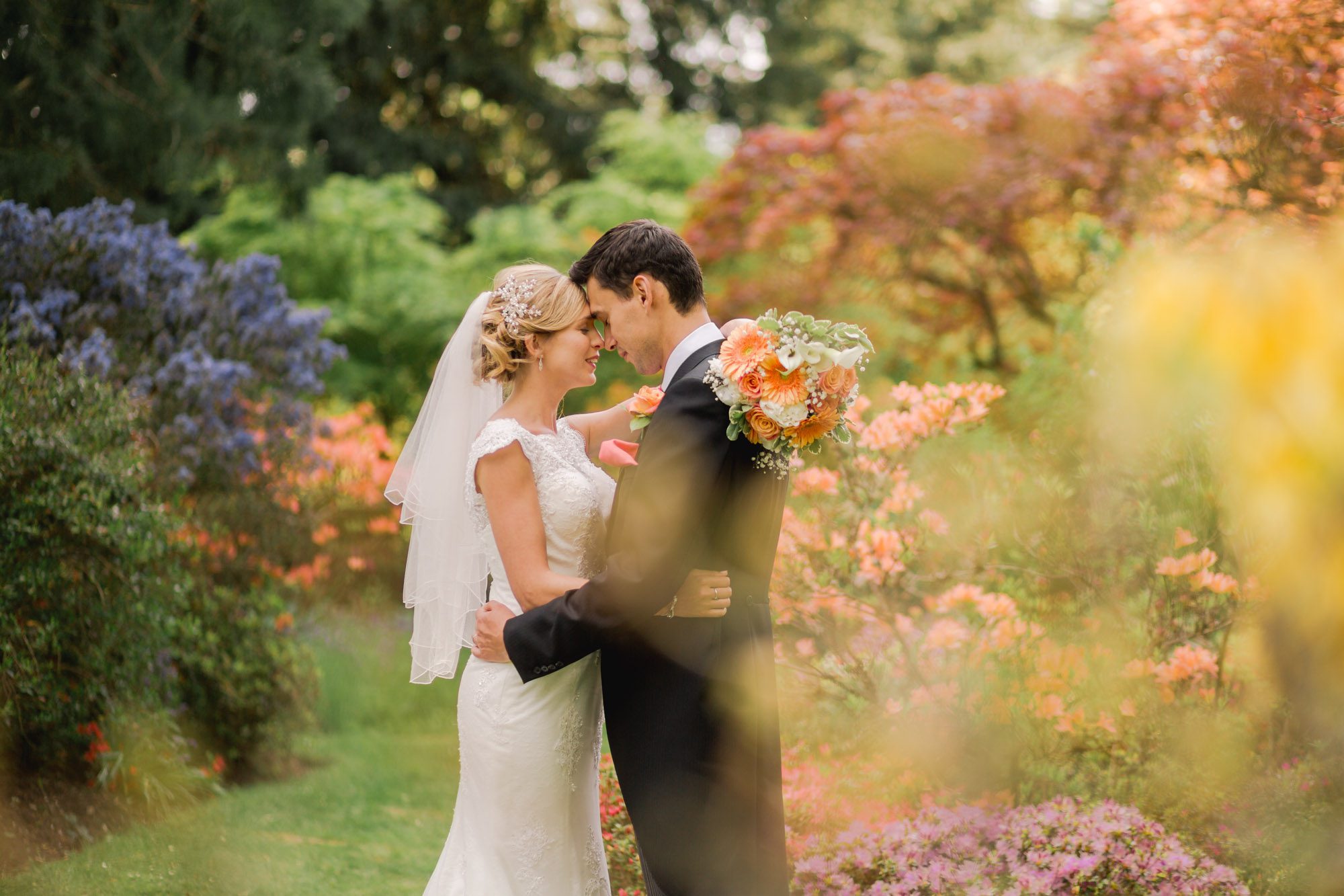 Bride and groom hug closely on their wedding day in the Ramster gardens in Summer.