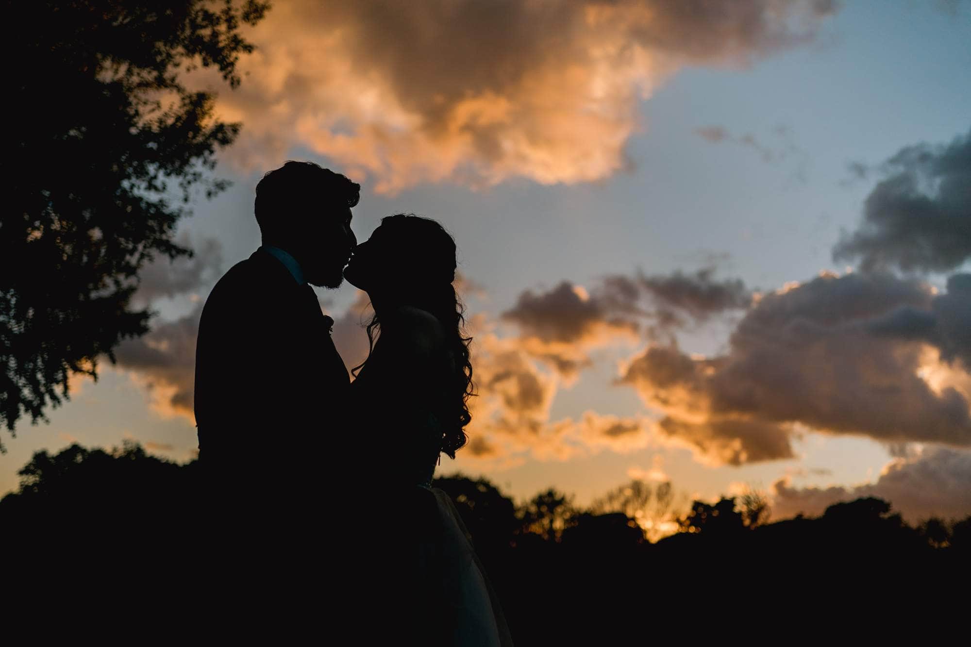 Bride and groom kiss at sunset on their wedding day in Worthing, West Sussex.
