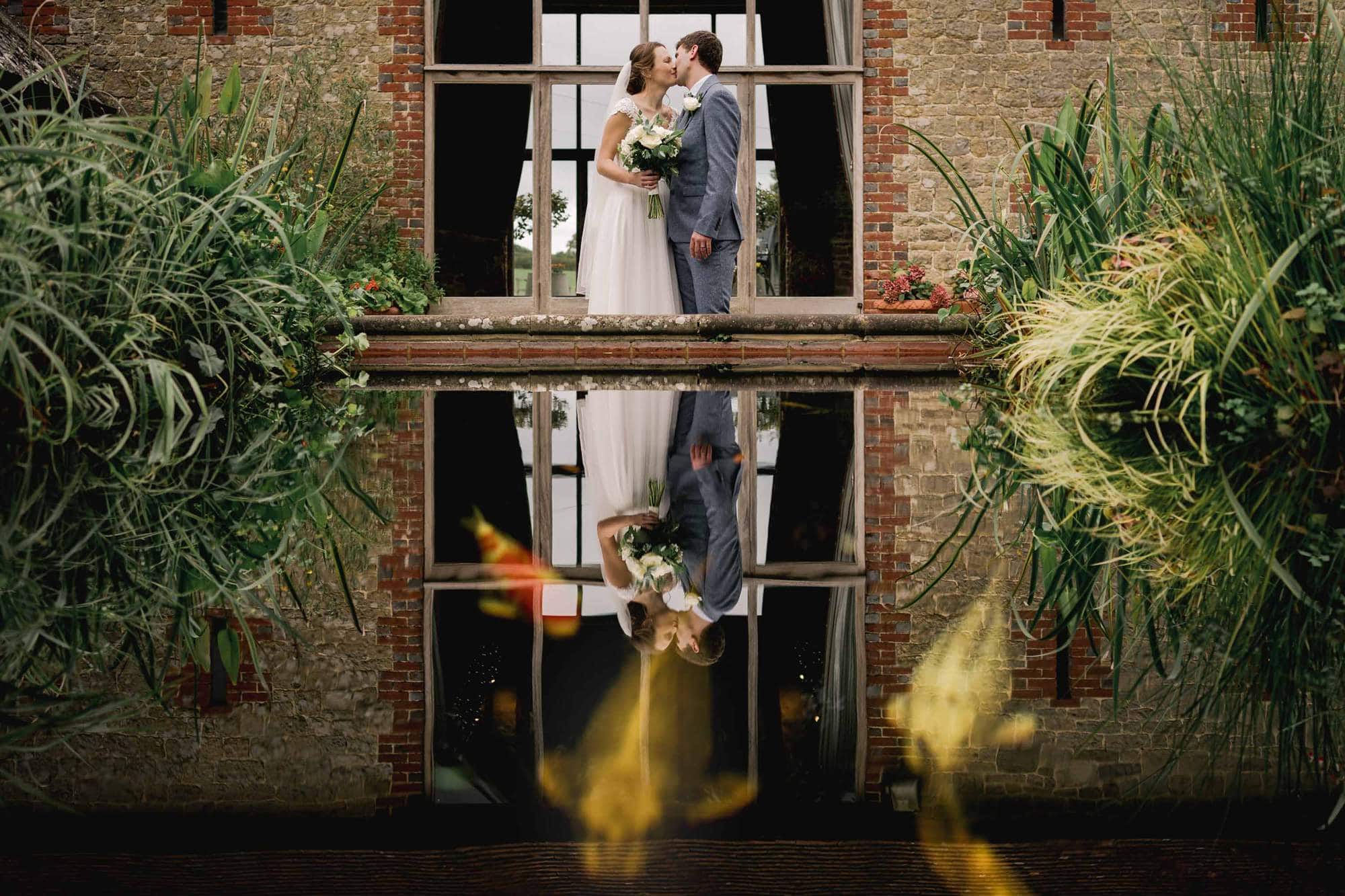 Rustic Wedding couple kissing at Bartholemew Barn in Sussex