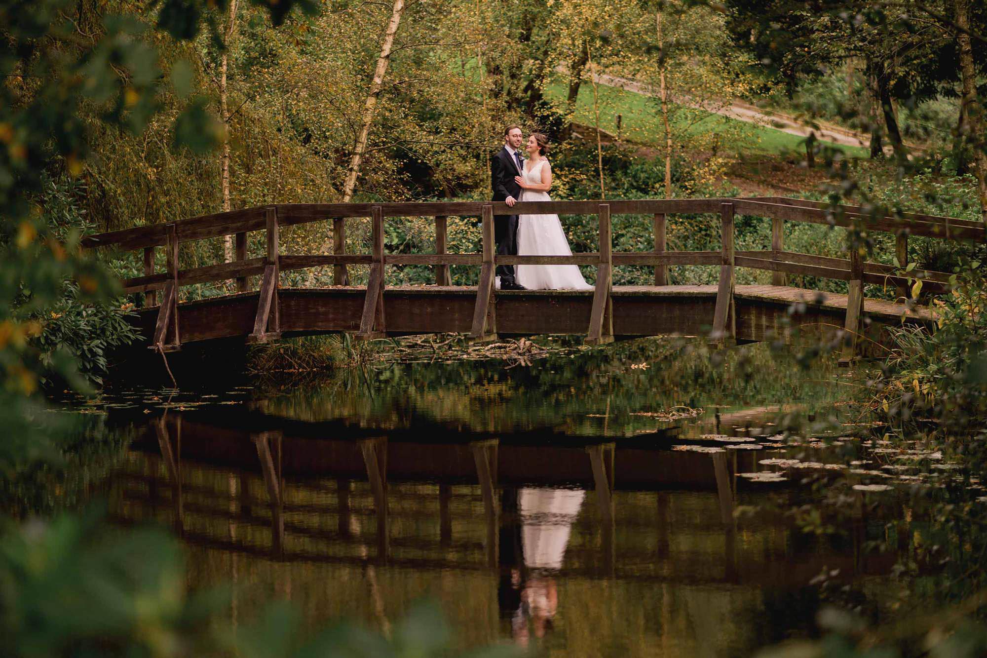 Bride and groom hug closely on a bridge at Salomons Estate in Tunbridge Wells.