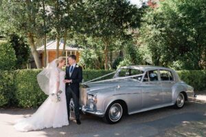 A couple in front of their wedding car at Nonsuch Mansion in Surrey.