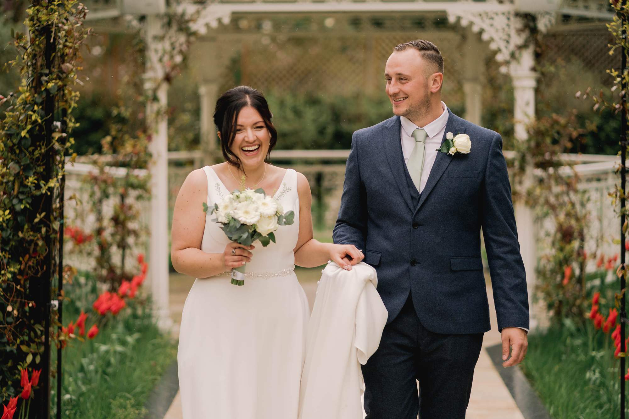 Newlyweds share a funny moment as they walk along at Guildford manor in Surrey.