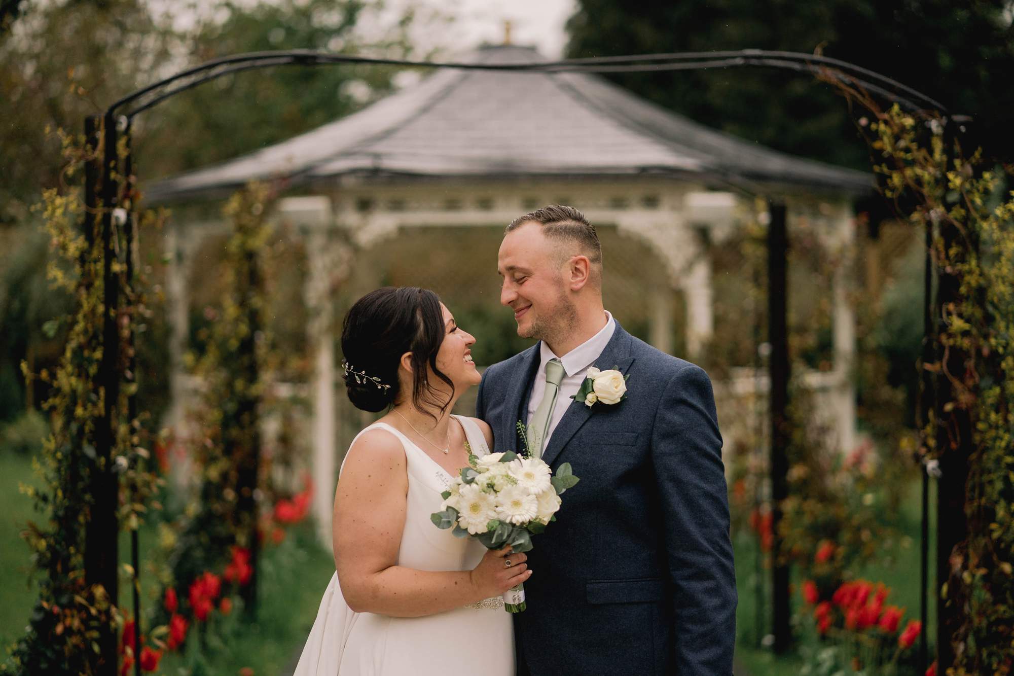 Bride and groom smiling in the gardens of Guildford manor in Surrey.
