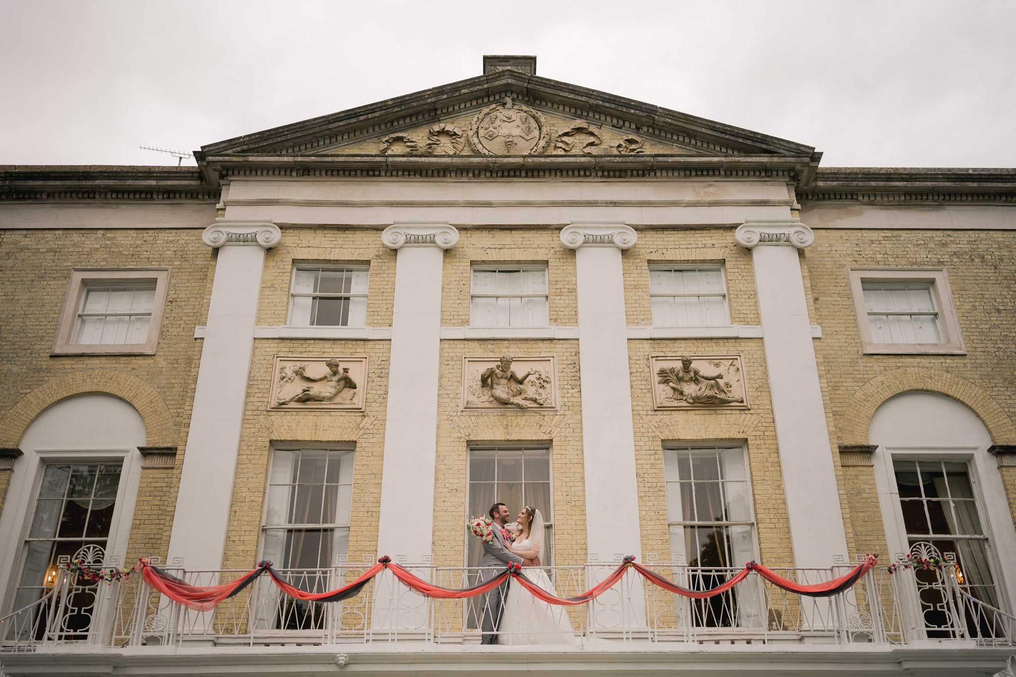 Bride and groom cuddle on their wedding day in front of Castle Goring in West Sussex.