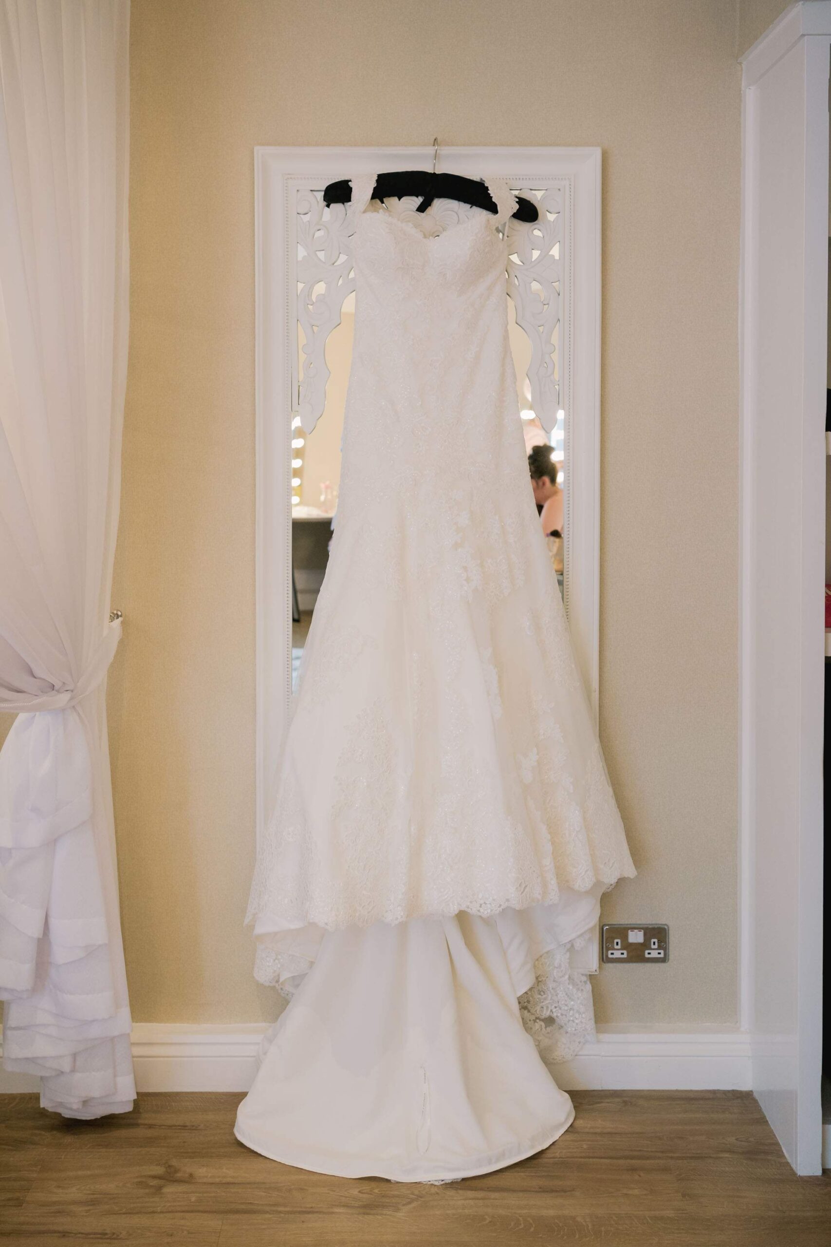 Traditional wedding dress hanging against a mirror at Old Thorns Hotel in Hampshire.