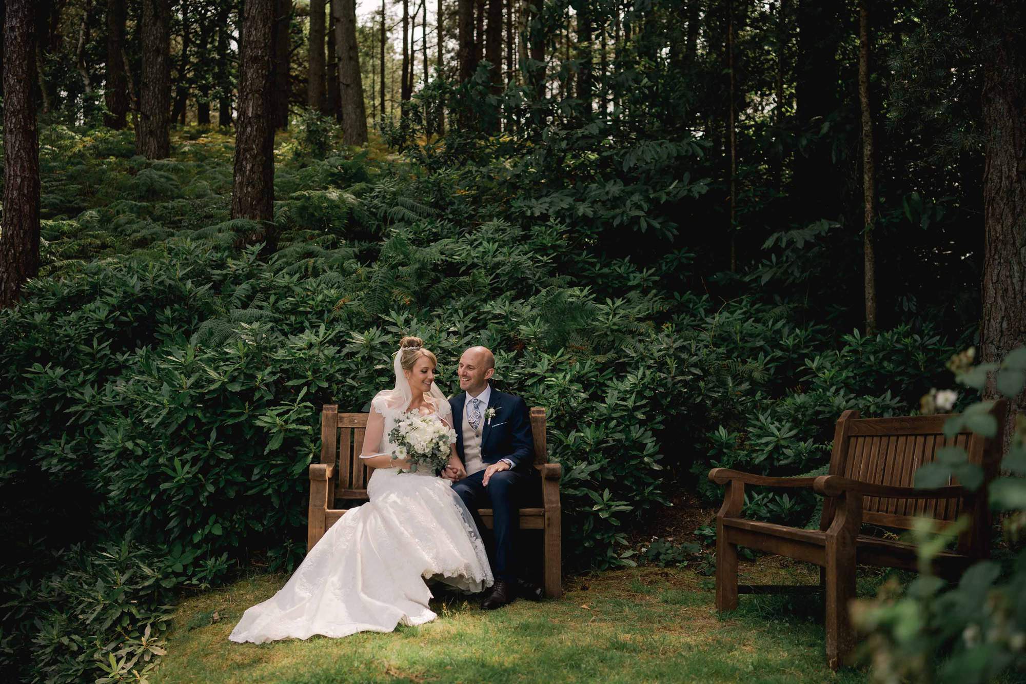 The bride and groom share a beautiful moment on a bench in the golf course at Old Thorns Hotel in Liphook.