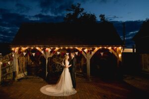 A bride and groom share an intimate moment under the twilight sky on their wedding day at Gildings Barn in Newdigate, Surrey.