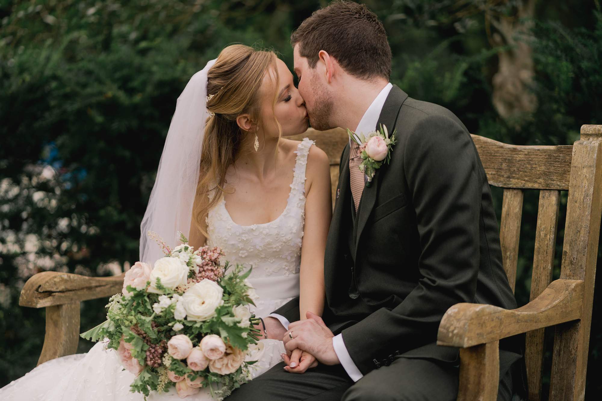 Newlyweds kiss on a bench at the Spread Eagle Hotel in Midhurst.