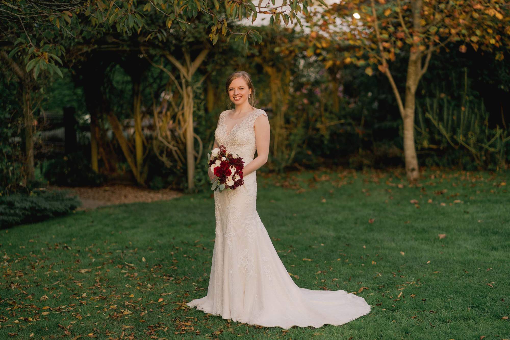 Bride holding her bouquet of red flowers at Rumbolds Farms wedding venue in Billingshurst, Sussex.