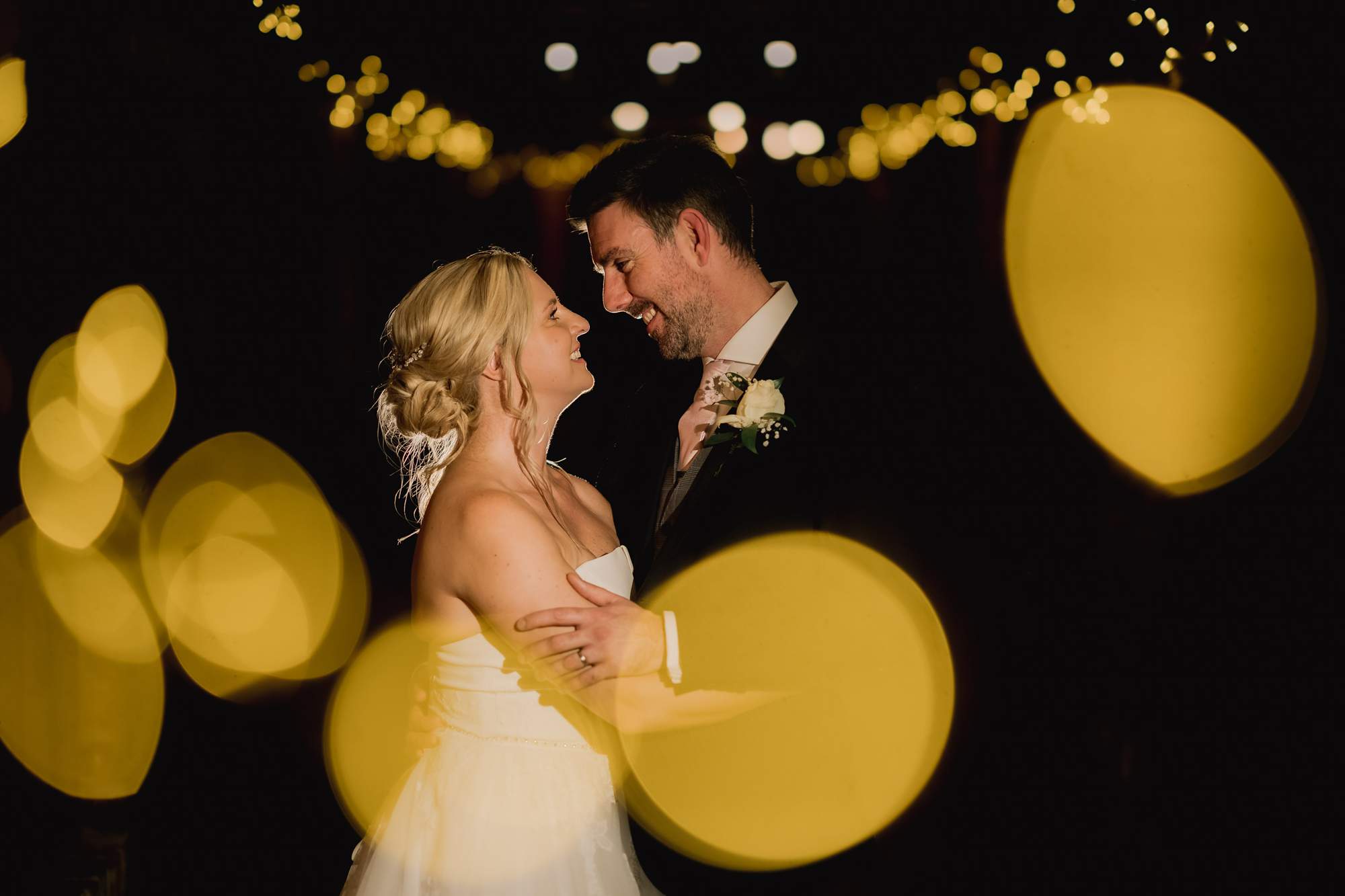 Newly married couple share a moment within a sea of fairy lights in Winchester.