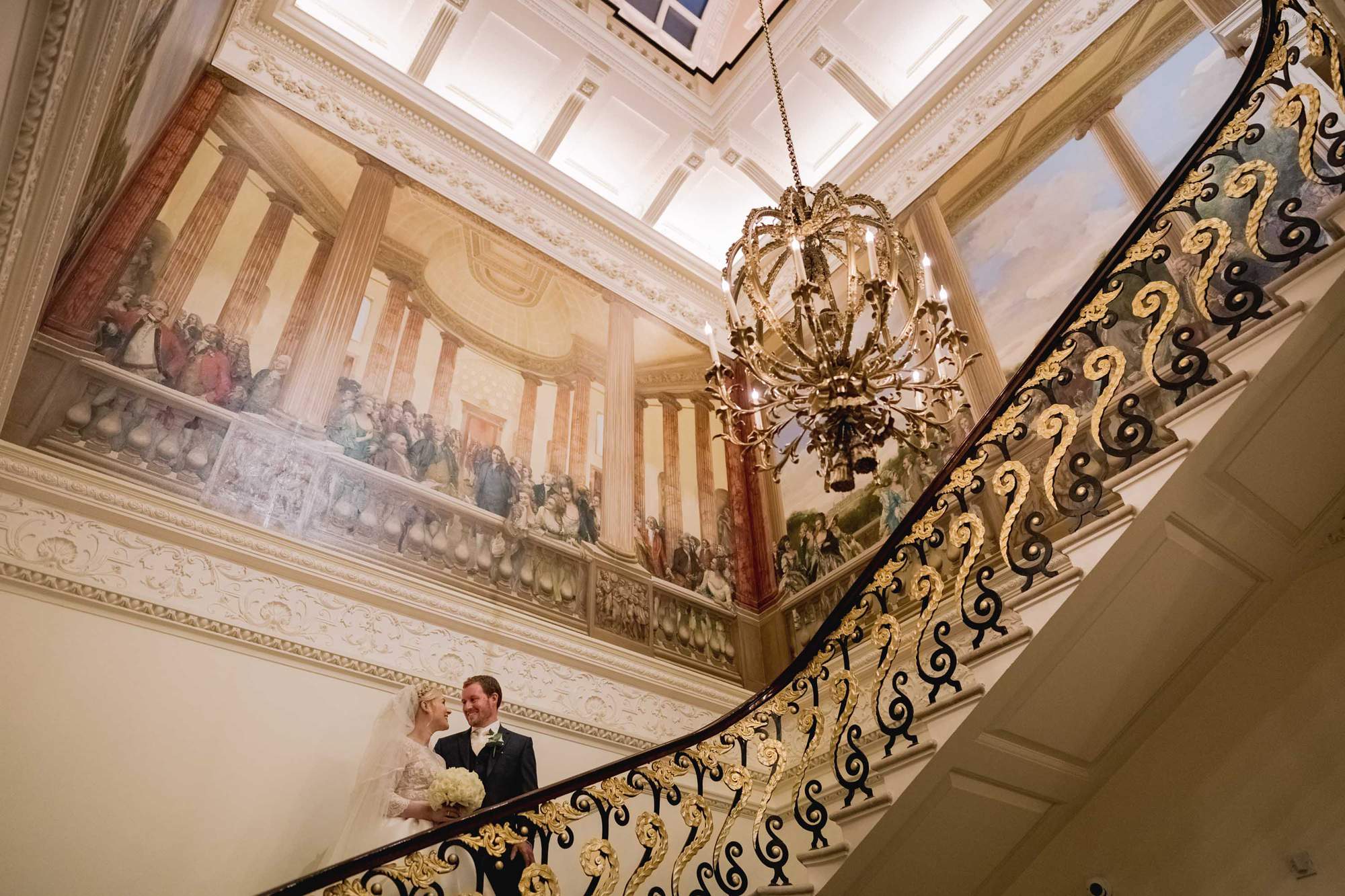 Bride and groom cuddle on the staircase at the Ritz Hotel in London.