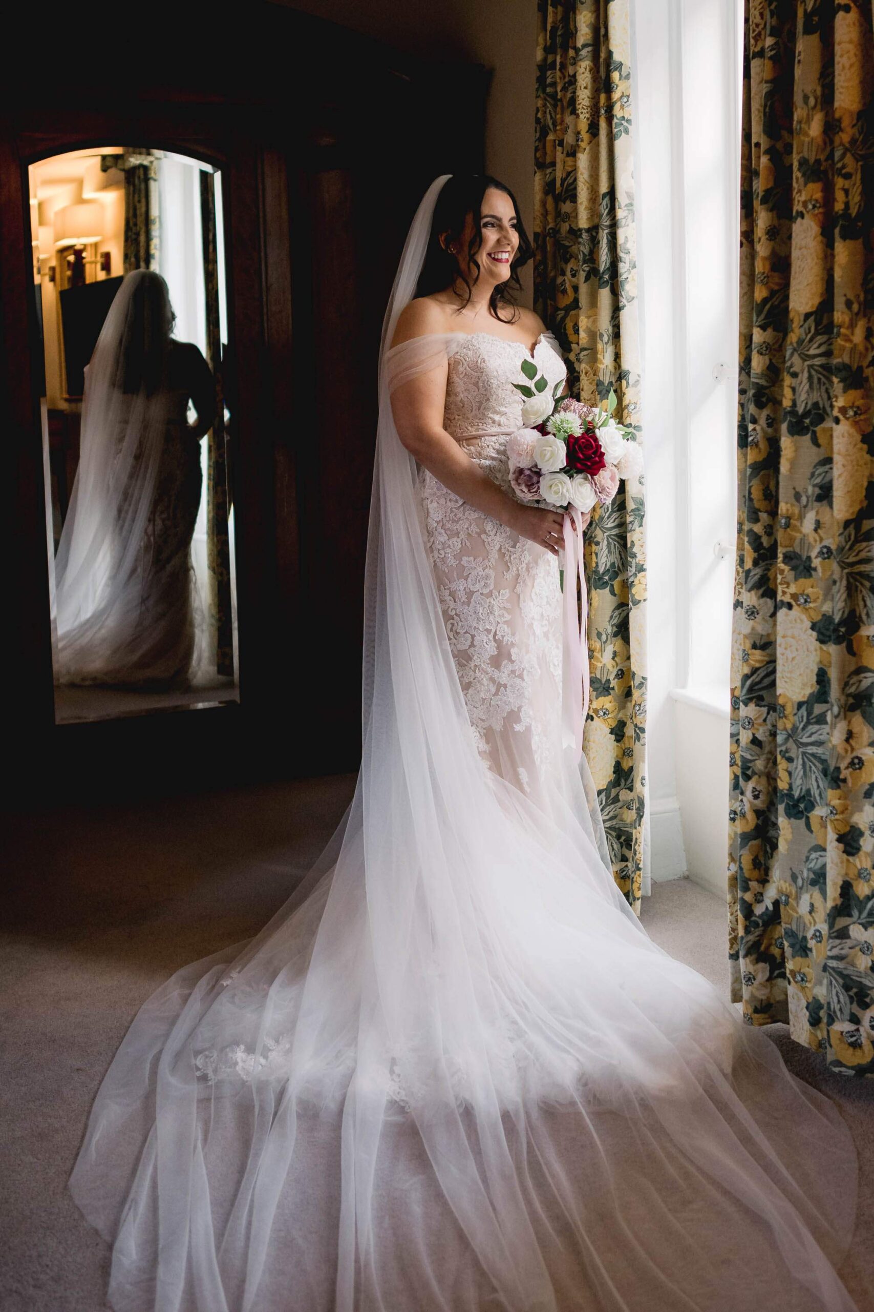 Bride looking out the window at Norfolk Arms hotel in Arundel on her wedding day.