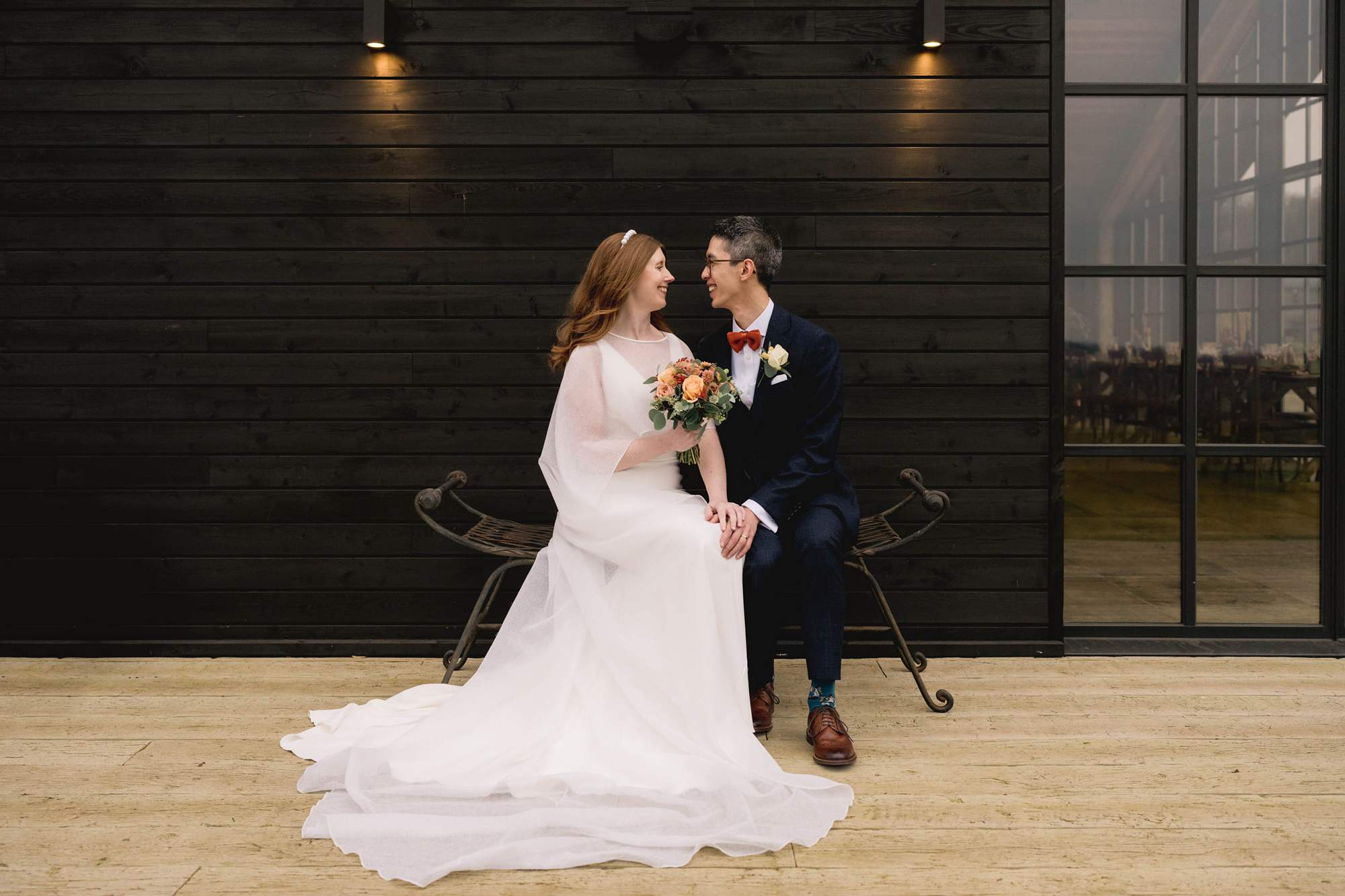 Bride and groom share a moment on a bench at the Barn at Botley Hill wedding venue.