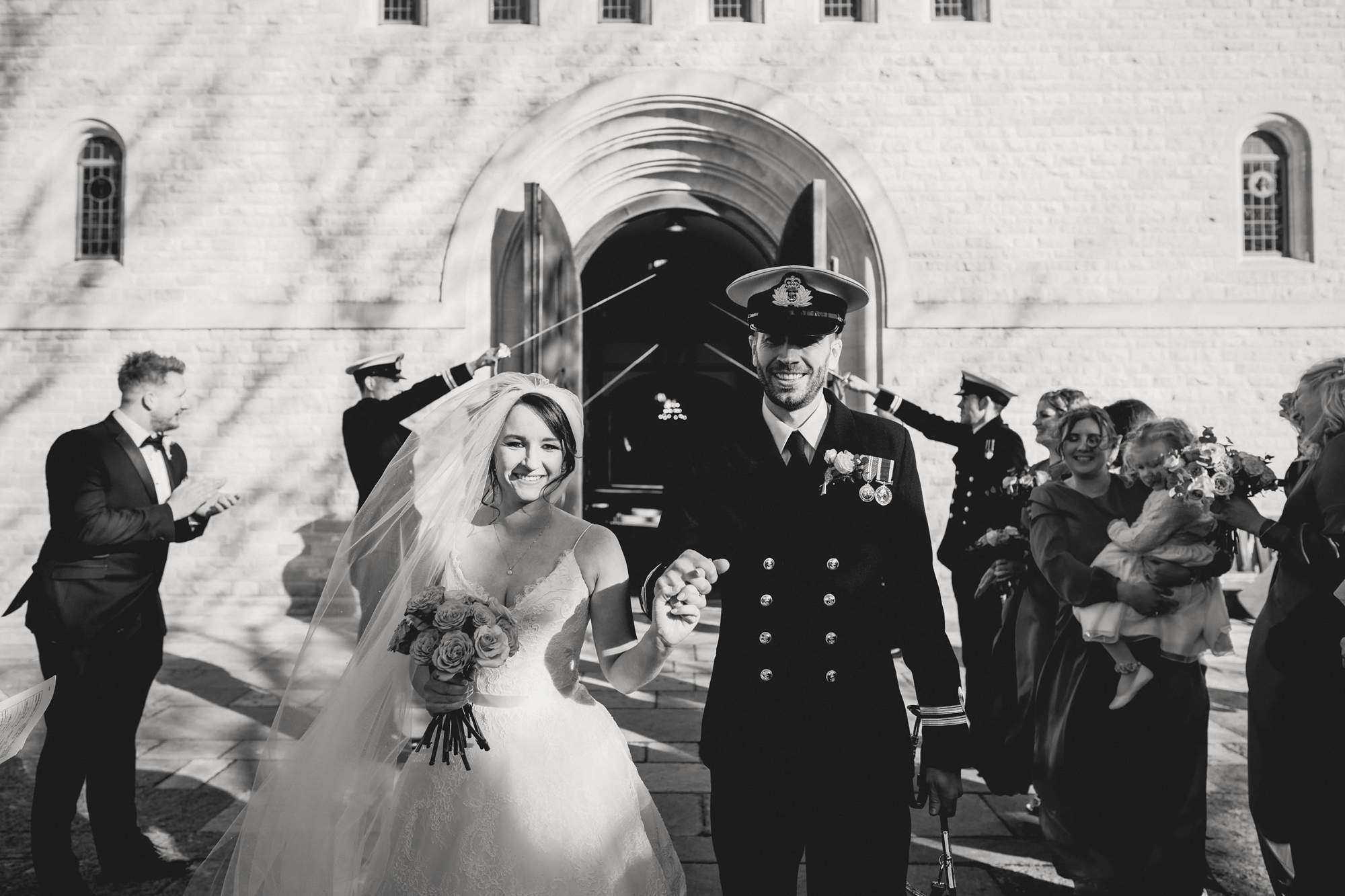 Naval wedding with bride and groom walking through swords.
