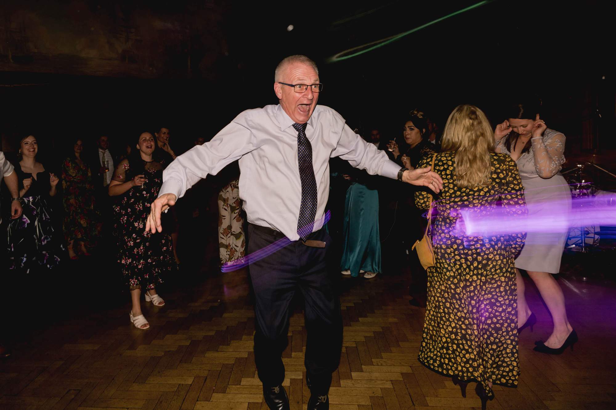 Father of the bride jumps in the air on the dance floor at a wedding.